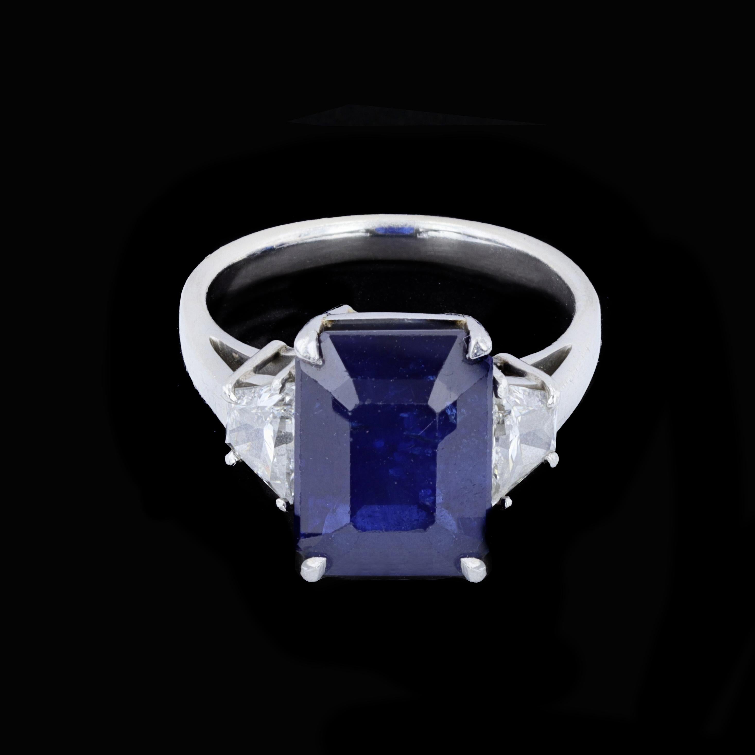 A spectacular three-stone sapphire and diamond vintage ring. The rich blue 7.59ctw emerald cut sapphire is supported by two trapezoid diamonds weighing 0.87 ctw and features a platinum setting.

