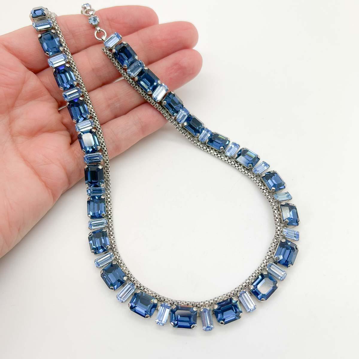 A Vintage Emerald Cut Crystal Riviere. Two of fashions most alluring features, the emerald cut stone and the riviere style necklace. The crystals emulating the colours of sapphires from the palest cornflour blue to rich dark blue.
Set in rhodium