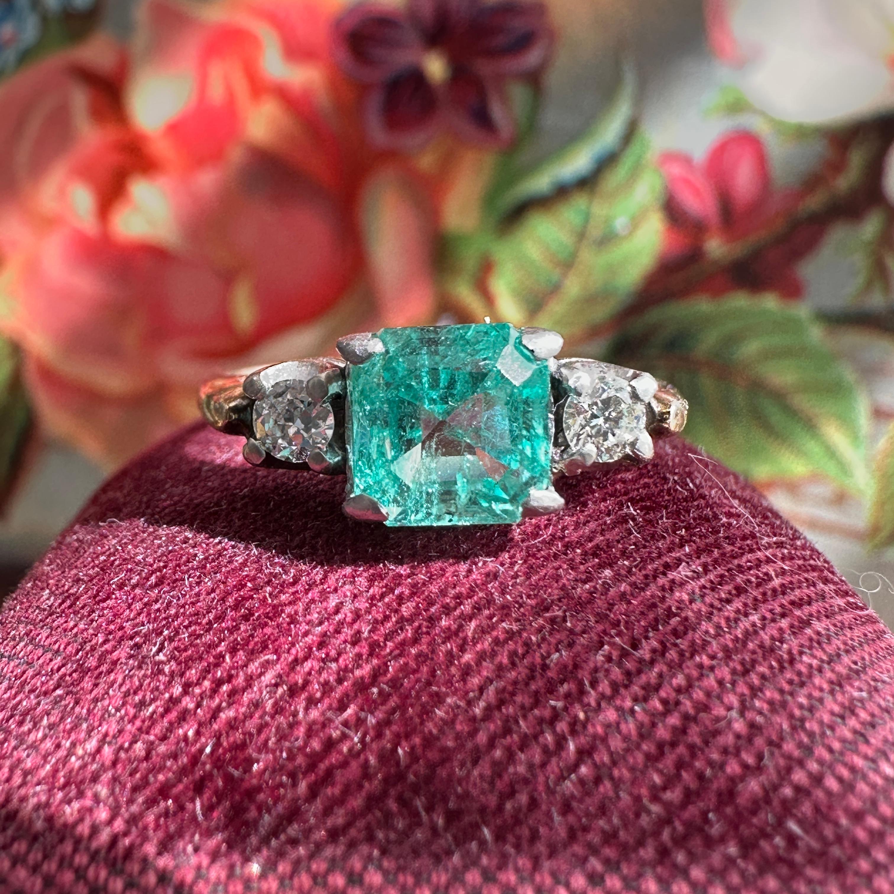 Details: 
Wonderful vintage roughly 1.22 carat emerald ring with pretty round diamonds on each side—the emerald is a beautiful shade of green with a lovely bluish green glow to it! The ring dates from the 1930-1940's. Vintage emerald and diamond