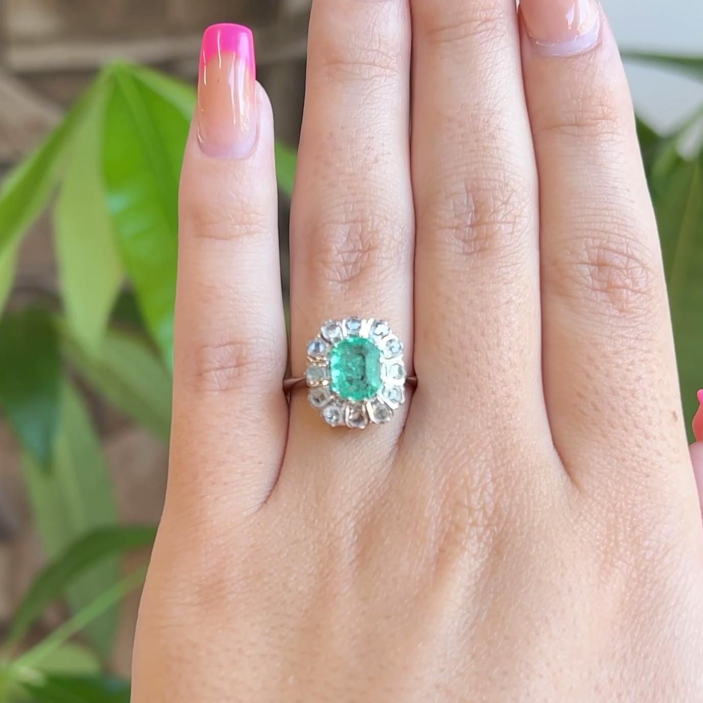 One Vintage Emerald Diamond 18 Karat White Gold Cluster Ring. Featuring one rectangular step cut emerald of approximately 1.15 carats. Accented by 12 rose cut diamonds with a total weight of approximately 0.75 carat, graded near-colorless, VS-SI