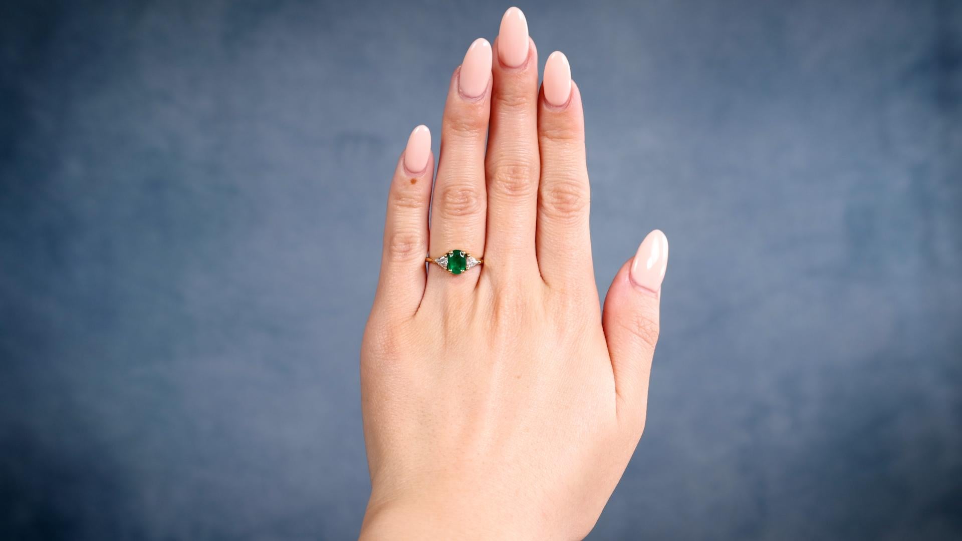 Ein Vintage Smaragd Diamant 18k Gelbgold Ring. Mit einem Smaragd im Kissenschliff mit einem Gewicht von etwa 0,70 Karat. Akzentuiert durch zwei Diamanten im Billionenschliff mit einem Gesamtgewicht von ca. 0,30 Karat, eingestuft in Farbe F und
