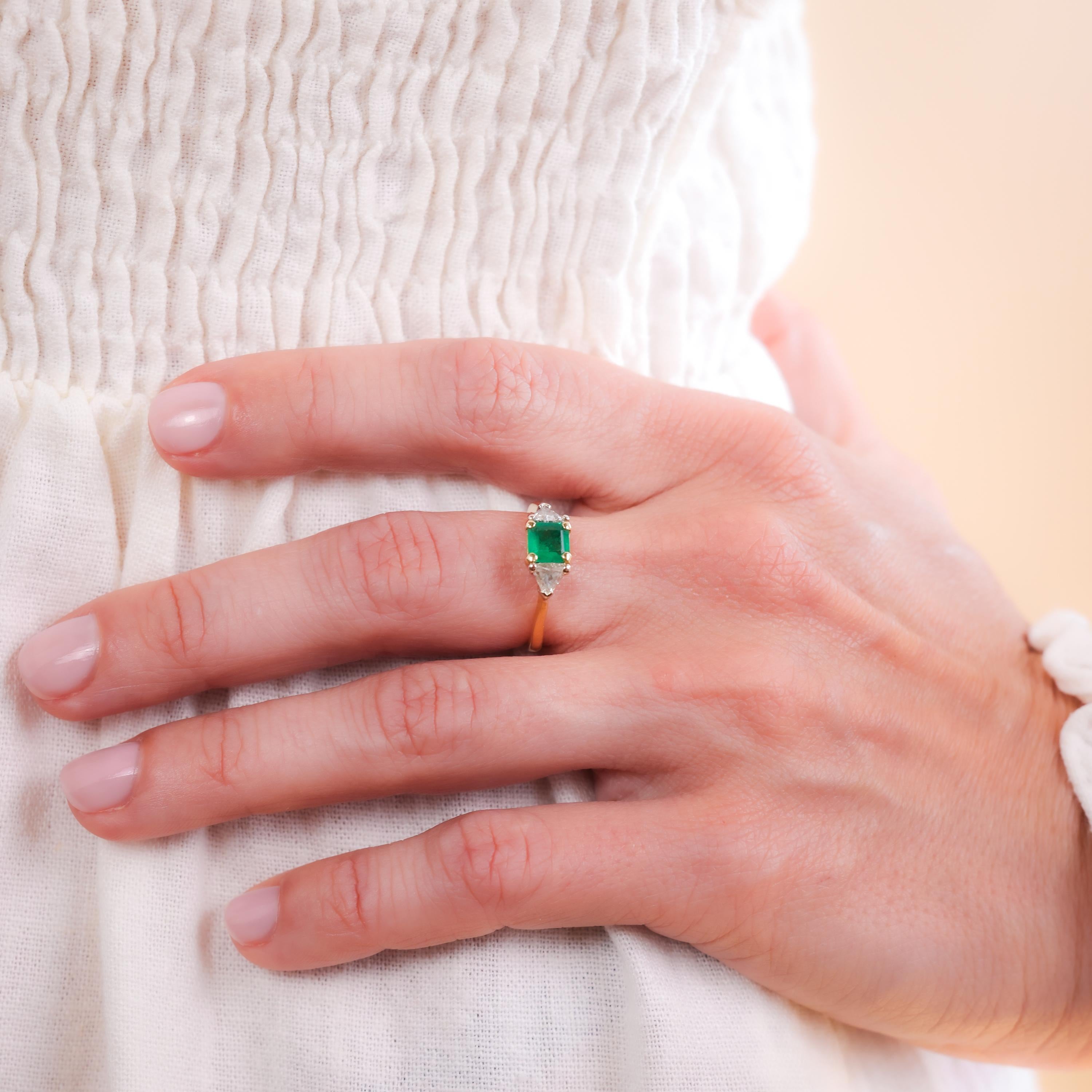 Center Stone: Emerald
Cut: Emerald
Weight: Approximately 0.5 Carats
Color: Green
Accent Stone: 2 Diamonds
Cut: Trillion
Weight: Approximately 0.35 Carats
Color: I
Clarity: SI
Metal: 18K Yellow Gold
Era: Vintage
Circa: 1980s
Hallmarks: 18K Purity