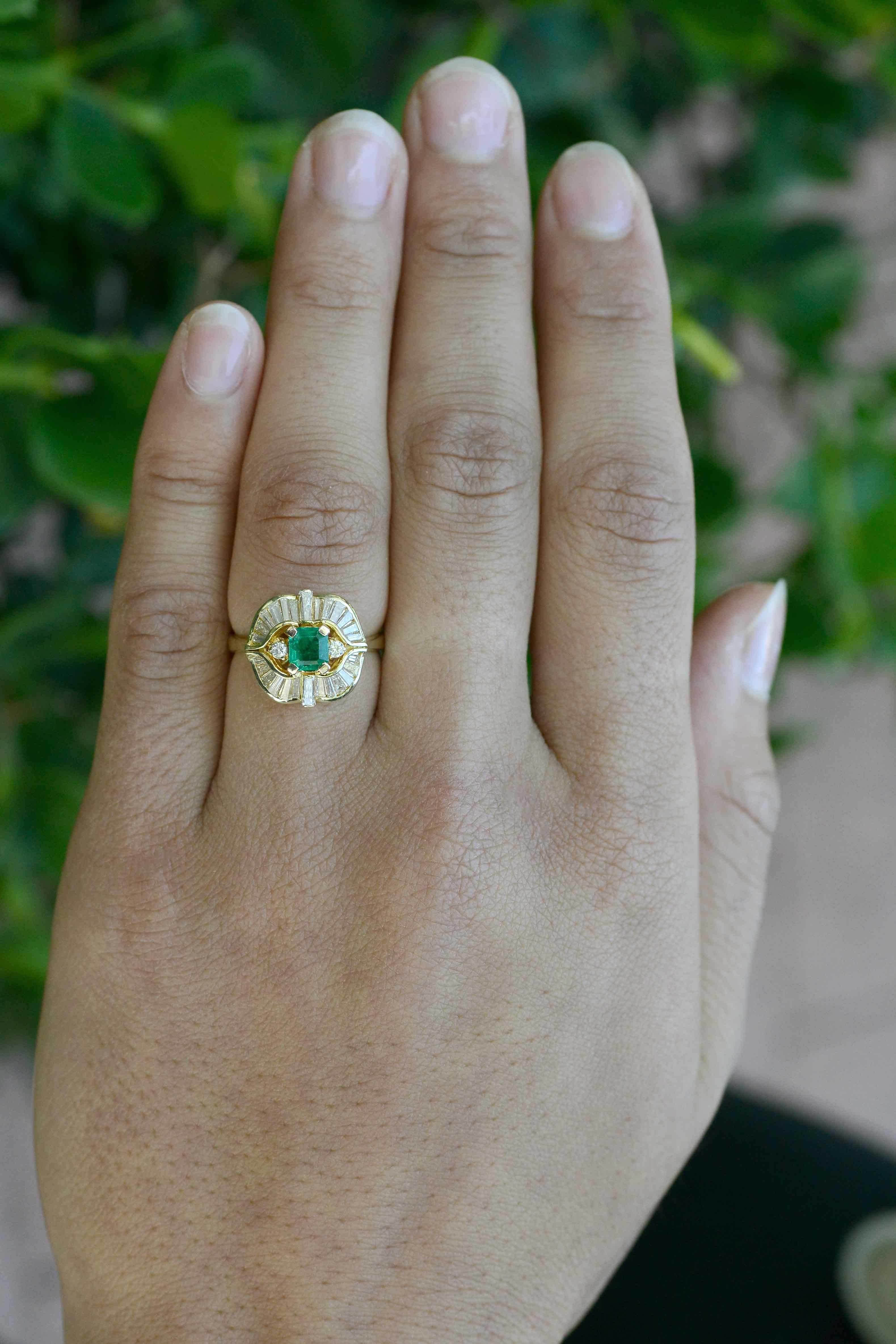 A sparkling and verdant vintage emerald and diamond cocktail ring in a flowing ballerina style. Eminently wearable as a gemstone engagement ring or right hand statement ring, the 1/2 carat emerald glows with a fire from within and is complimented by