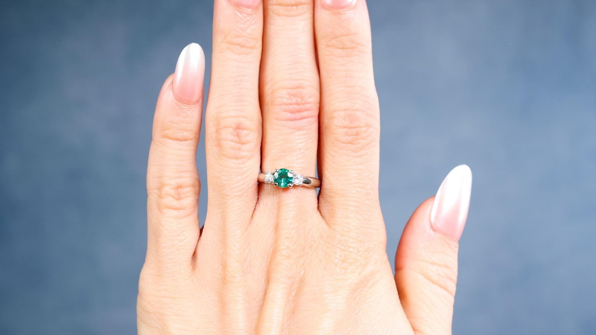 One Vintage Emerald Diamond Platinum Three Stone Ring. Featuring one round brilliant cut emerald of 0.43 carat. Accented by two round brilliant cut diamonds with a total weight of 0.20 carat, graded H-I color, SI clarity. Crafted in platinum with