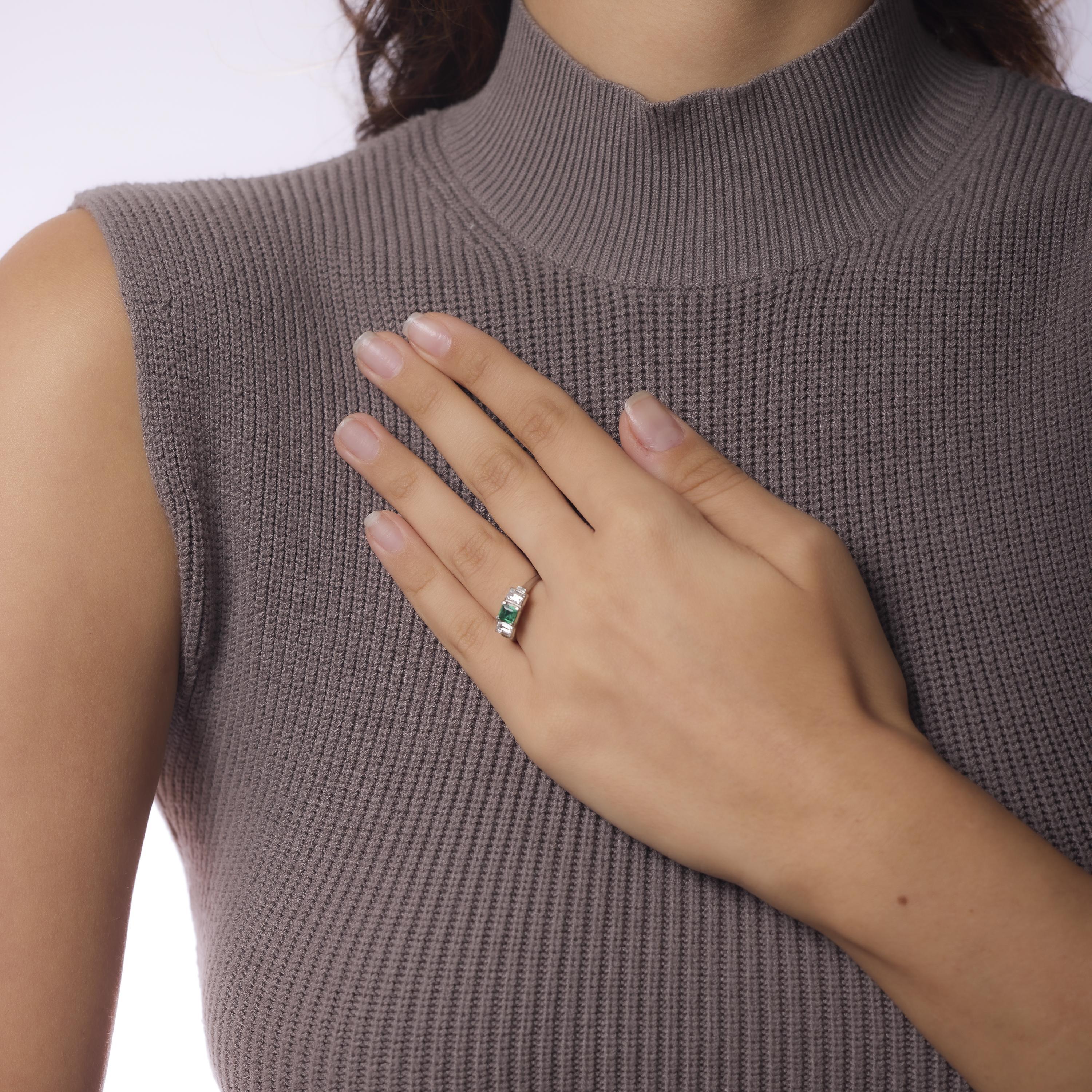 This vintage platinum three stone ring showcases a vivid .45 carat emerald flanked by two emerald cut diamonds totaling .78 carats. With F color and VS clarity, the diamonds bring crisp brilliance to the rich green centerpiece. Crafted in the 1990s
