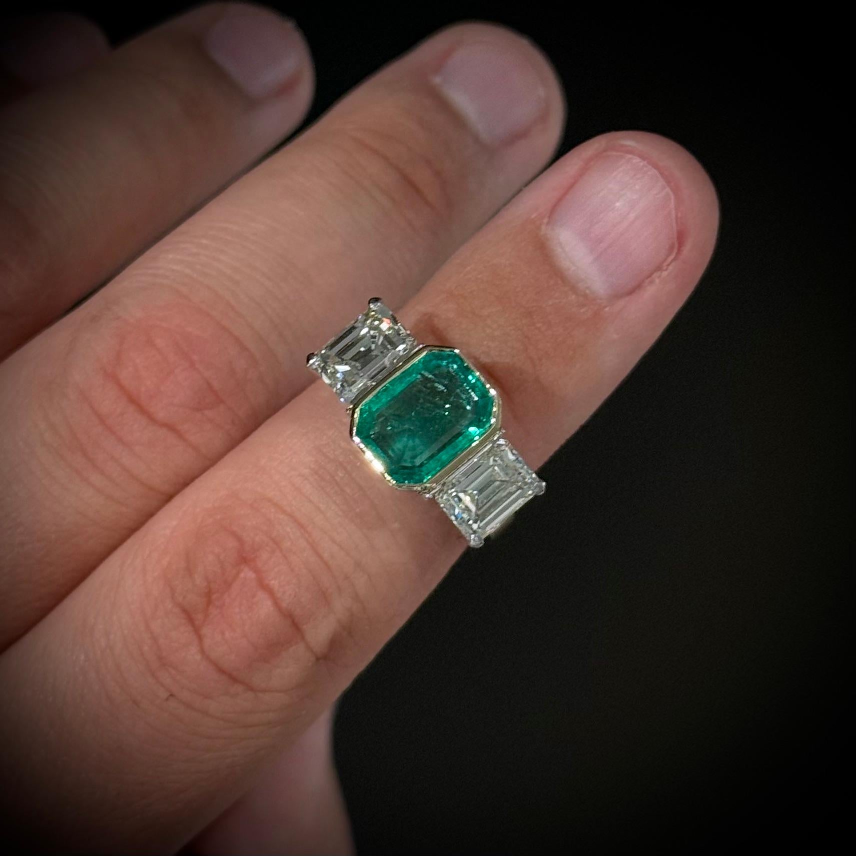 Vintage Emerald and Diamond Three-Stone Engagement Ring in Platinum and Yellow Gold, Portugal, 1990s.

A classic and elegant three-stone ring centering a richly saturated emerald-cut emerald, bezel-set in warm 19.2kt yellow gold and flanked by two