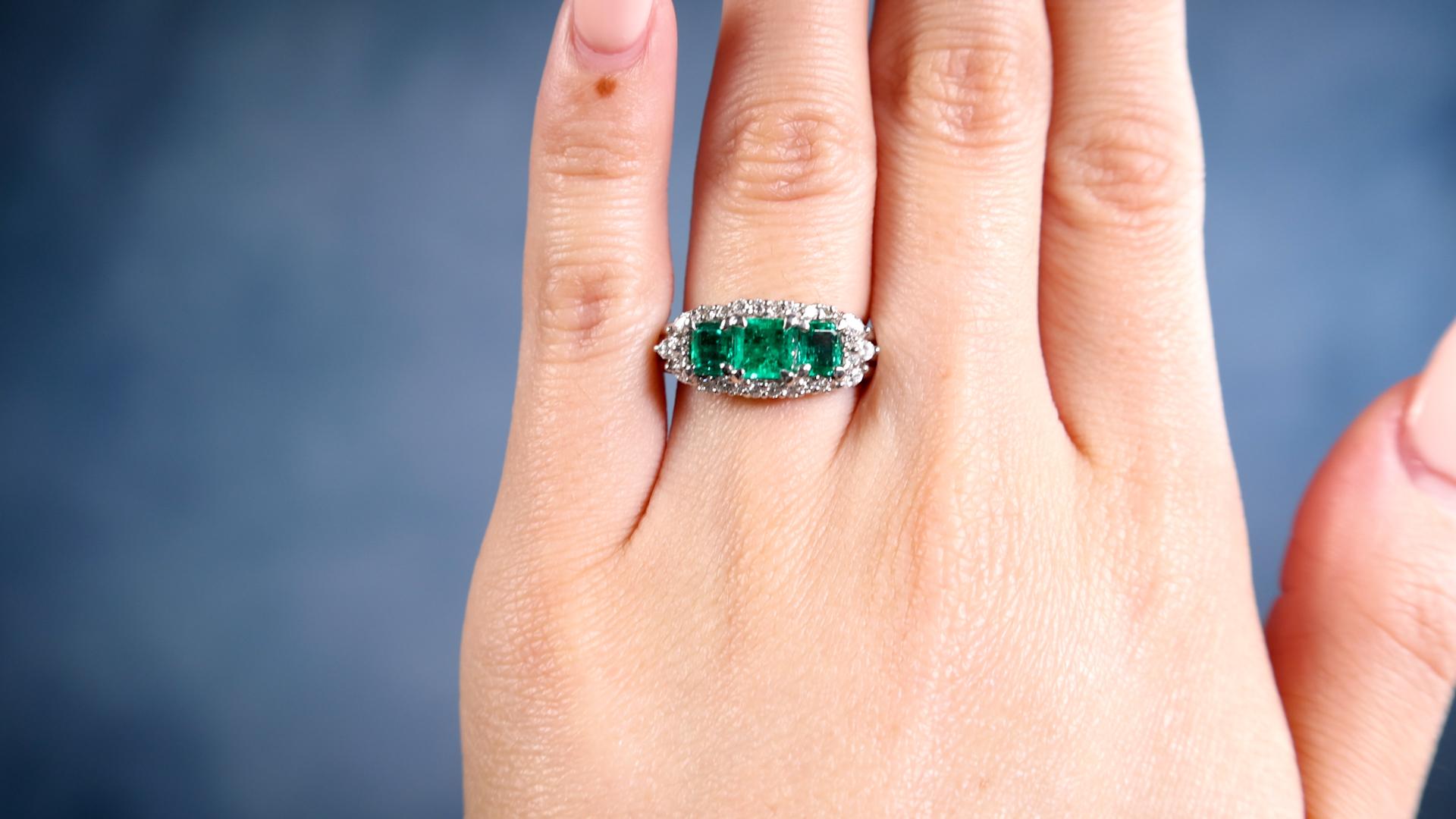 One Vintage Emerald Diamond Three Stone Platinum Ring. Featuring three octagonal step cut emeralds with a total weight of 1.03 carats. Accented by six marquise and 20 round brilliant cut diamonds with a total weight of 0.45 carat, graded
