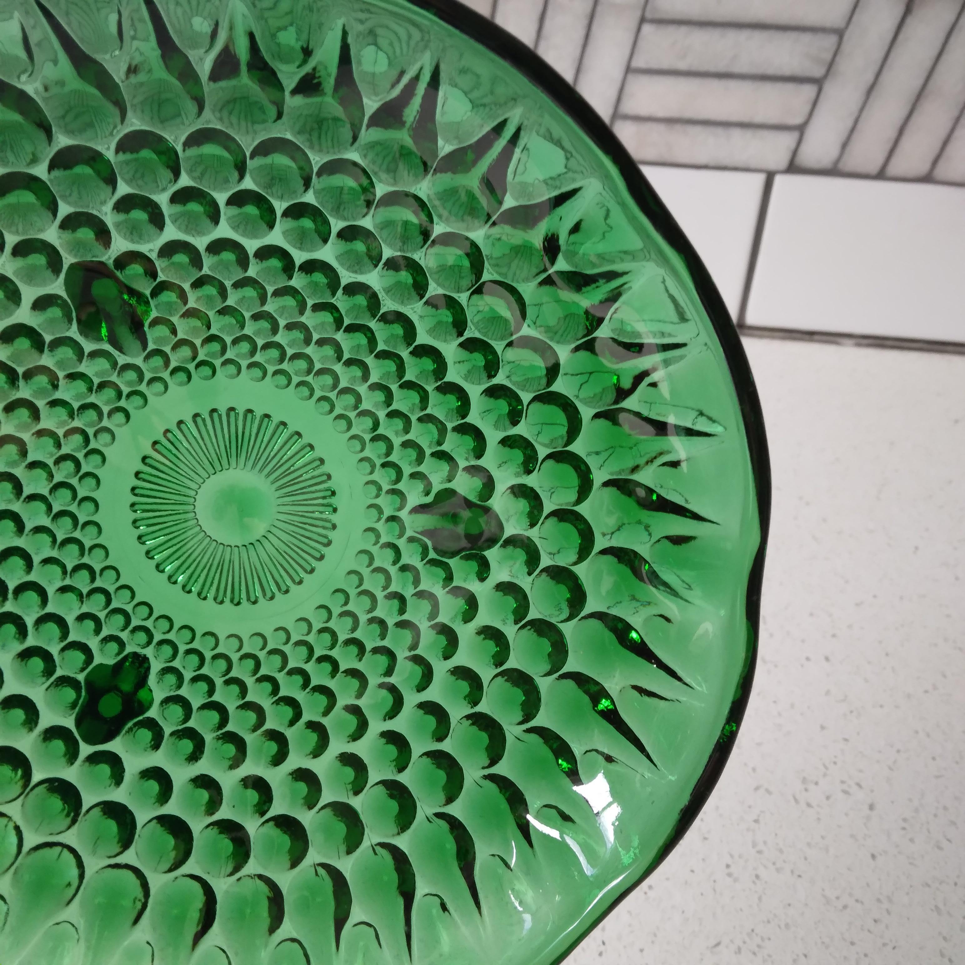 Gorgeous emerald green glass catches and scatters light in a mesmerizing way. We love the chunky hobnail design and quaint feet. The thick walled glass of this vintage piece is in excellent condition for its age.
