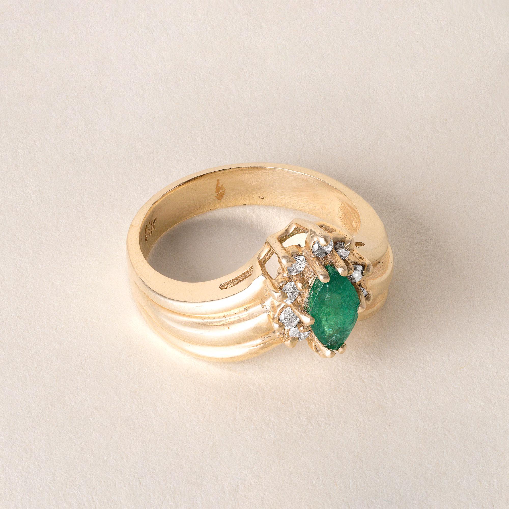 Circa 1980's
~0.75 carat emerald marquise cut
surrounded by 10 round brilliant cut diamonds
Curved wide ribbed cigar band
4.4 grams
14K marked in shank
Ring size 6.5
