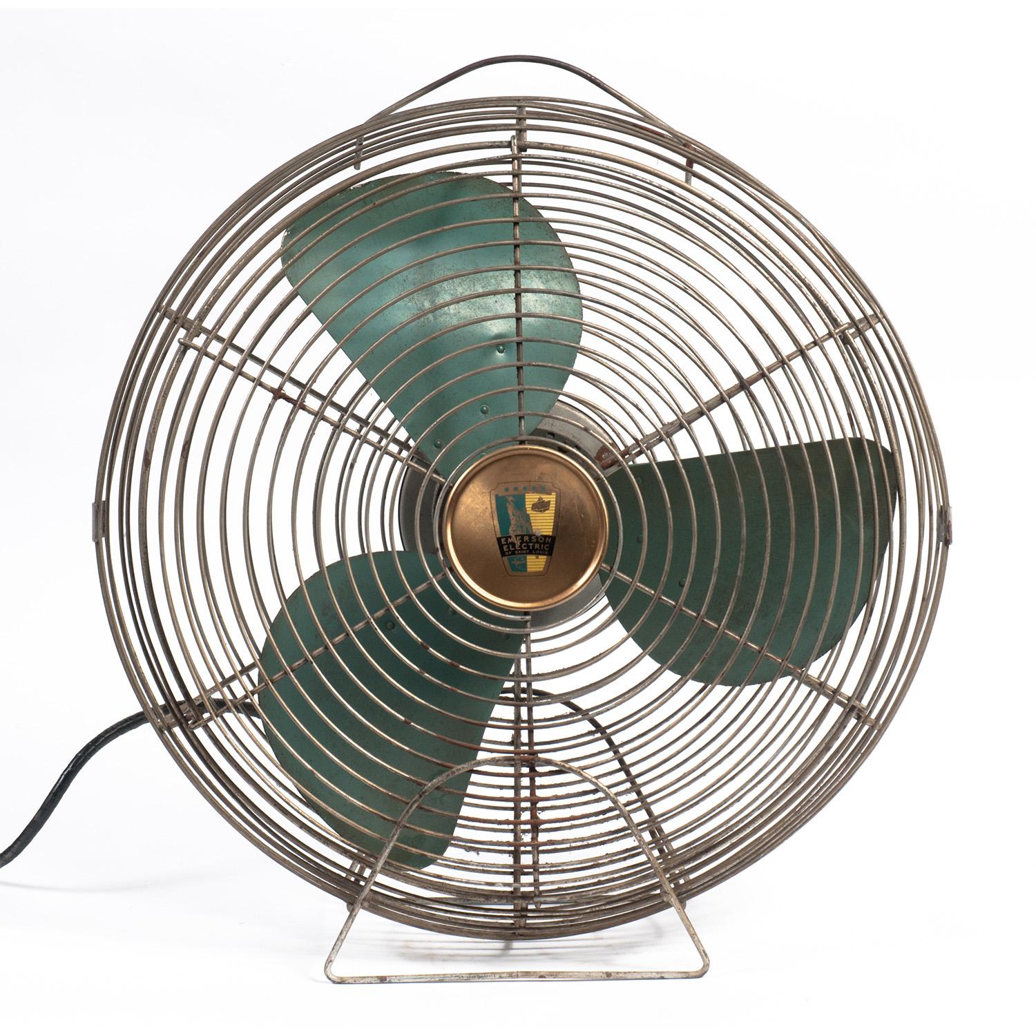 Large vintage fan with with turquoise blades and manufacturer medallions on front and back reading 
