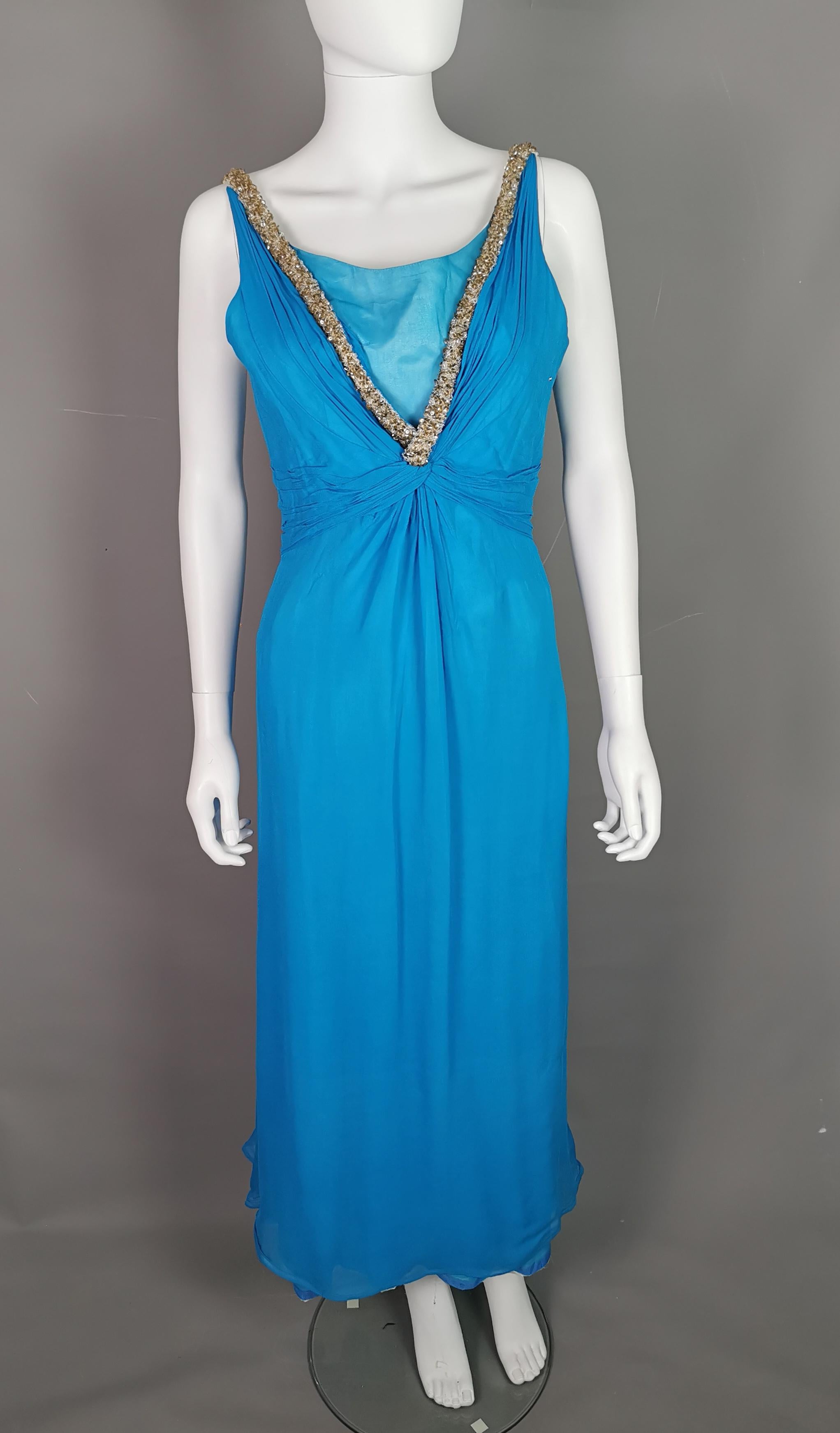 Ein wunderschönes Abendkleid aus den 1970er Jahren von Emma Domb.

Dieses Kleid hat einen Hauch von Prinzessin, es ist lang und aus leuchtend blauem Seidenchiffon. Der V-Ausschnitt ist mit einem Overlay und einer Schamhaube versehen.

Die Träger und