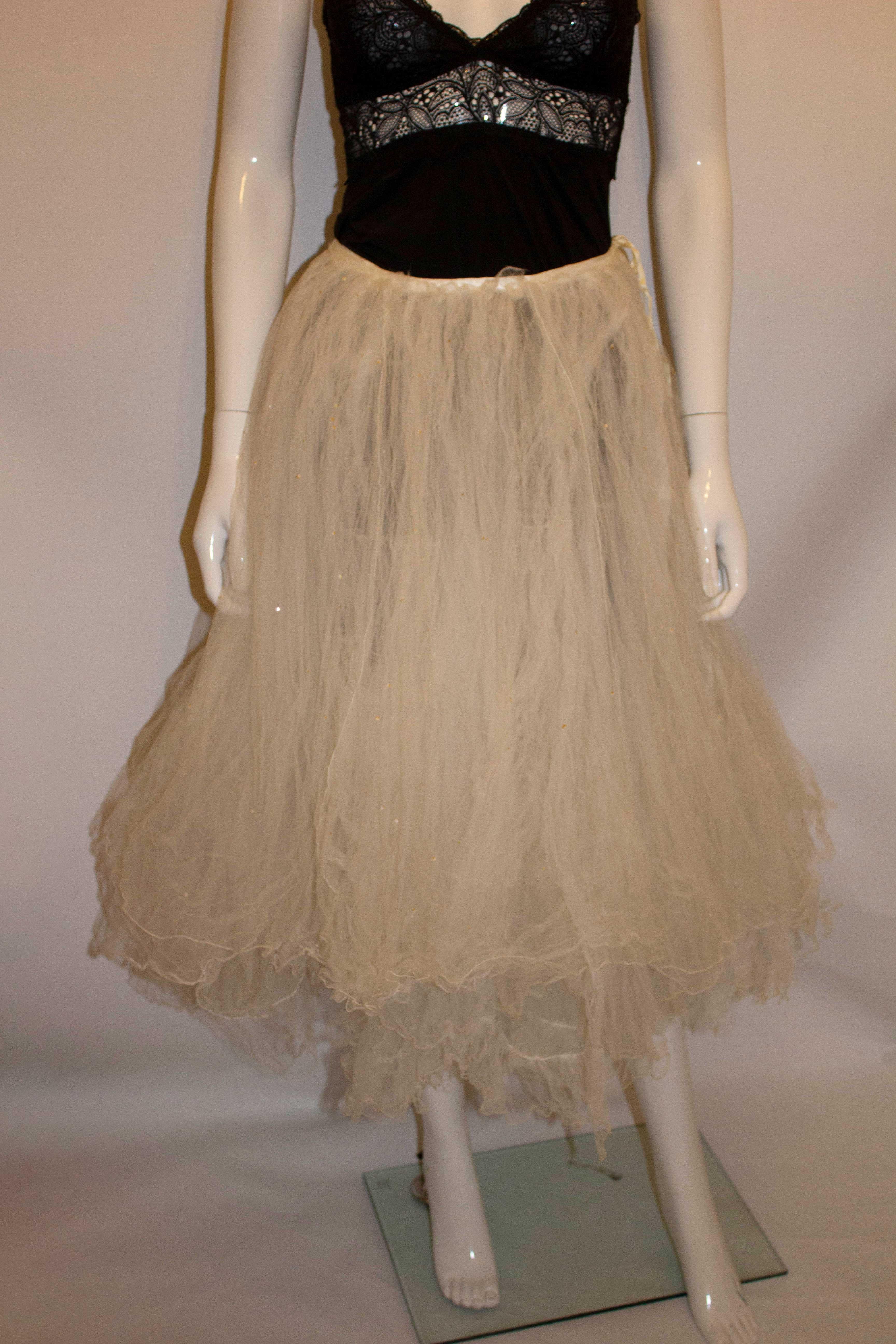 
A wonderful net skirt by Emmanuel ( designers of Princess Diana wedding dress). The skirt has a satin waist band and tie ribbon fastening. It is made of several layers of net with sequin detail. 
Measurements : waist 25'',length 28''