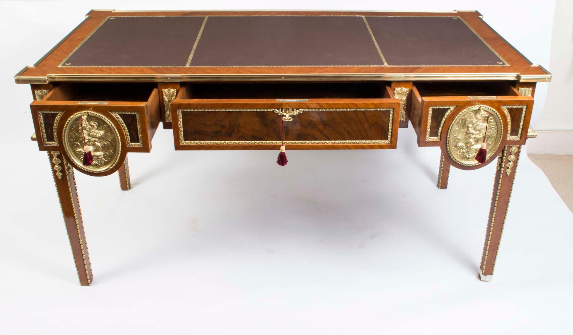 This is a grand Empire Revival Vintage writing table in walnut with beautiful ormolu mounts and tooled leather writing surface, dating from the last quarter of the 20th century.

The table features large ormolu circular ormolu plaques around its