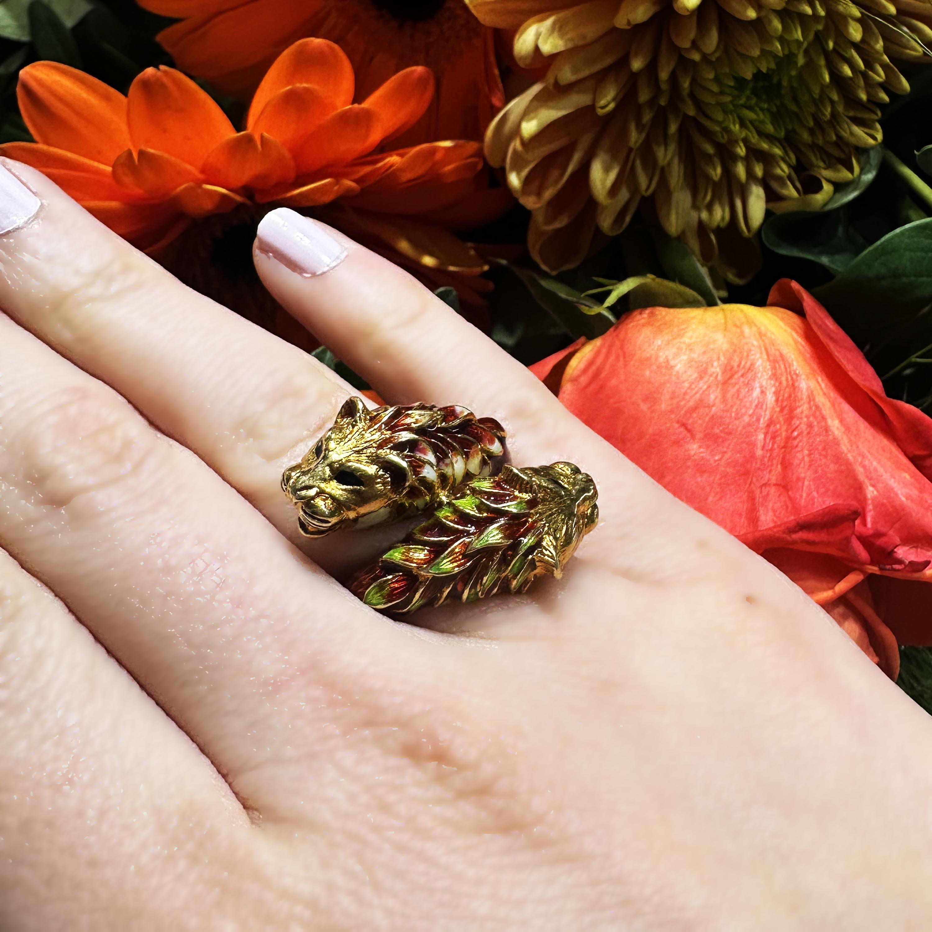 An enamel and gold double lion head ring by Zolatas, with red, green, white and black bass taille enamel on 18ct gold stamped 750. 

The Greek firm of Zolotas was founded in 1895 in Athens at the foot of the Acropolis by Efthimios Zolotas. He was