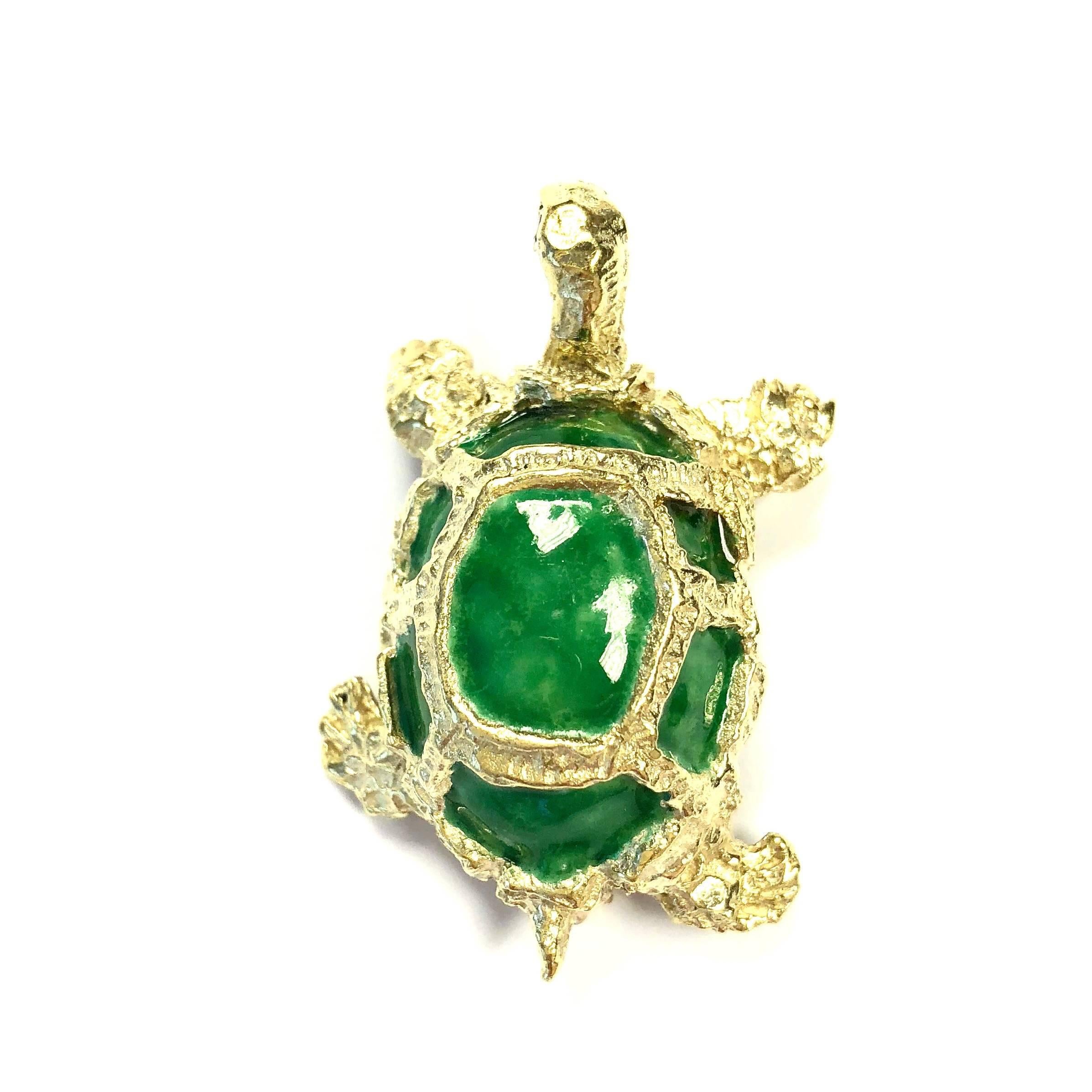 Crafted in 14K yellow gold, the turtle features green enamel shell and ruby eye accents. 
Measurements:
1 5/8 inch H (41.5 mm) x 1 inch W (25 mm) x 9/16 inch D (14.5 mm)
Weight: 18 grams