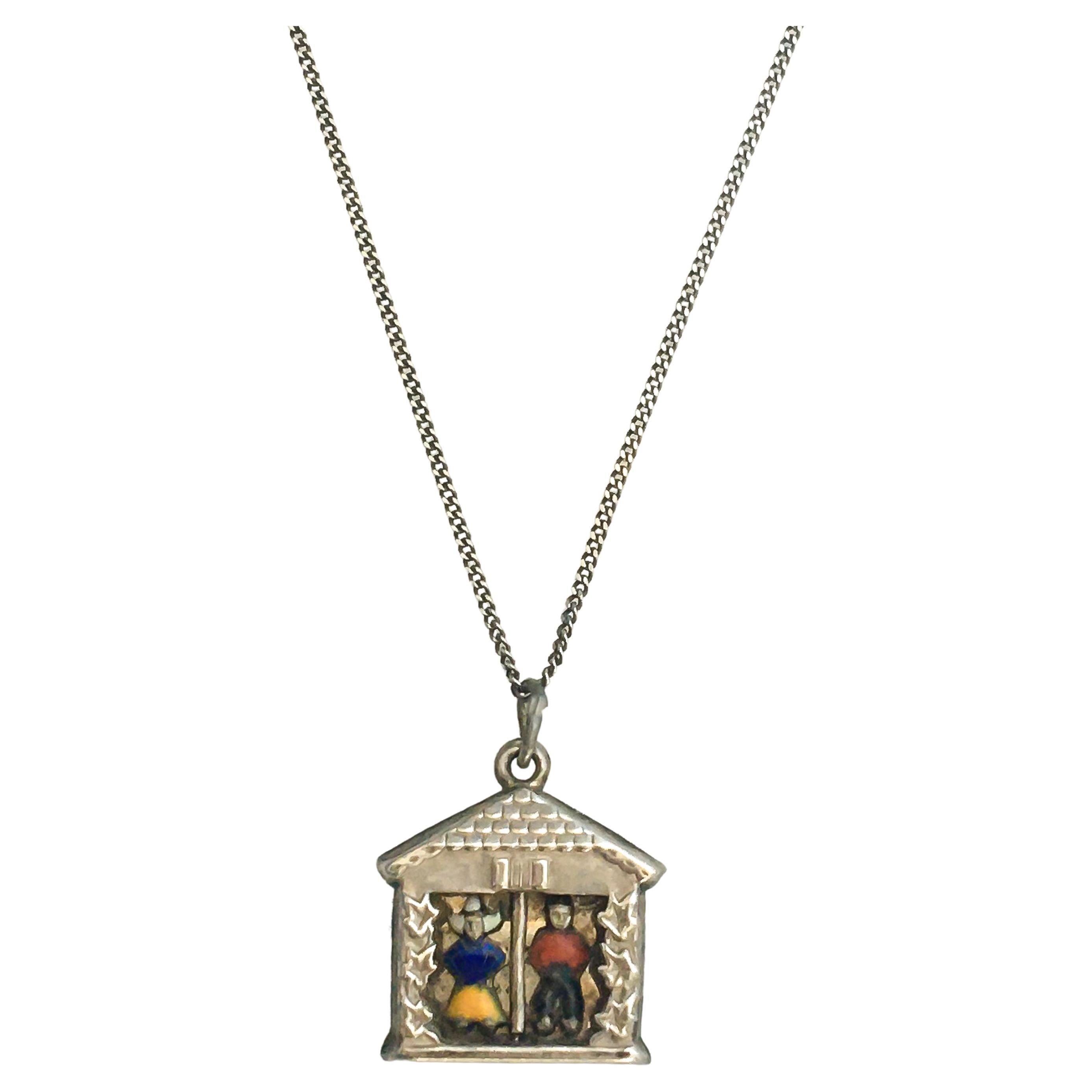 A three-dimensional enamel weather house charm pendant made of silver. This charm shows nicely detailed enameled farmers, a farmer and a farmers wife, standing next to each other. The charm can be worn as an addition to your charms bracelet or alone