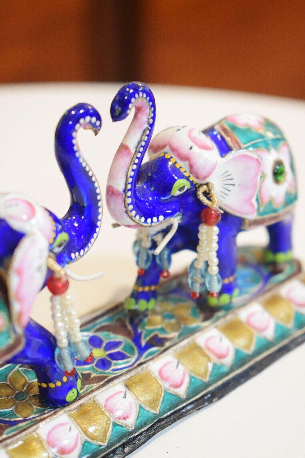 A beautiful vintage Indian enameled precious silver metal base figurine of two elephants meeting trunks to form a heart shape set on a decorative base.
Bright royal blue accompanied with pink, turquoise and gold..
Adorable heart shape being formed