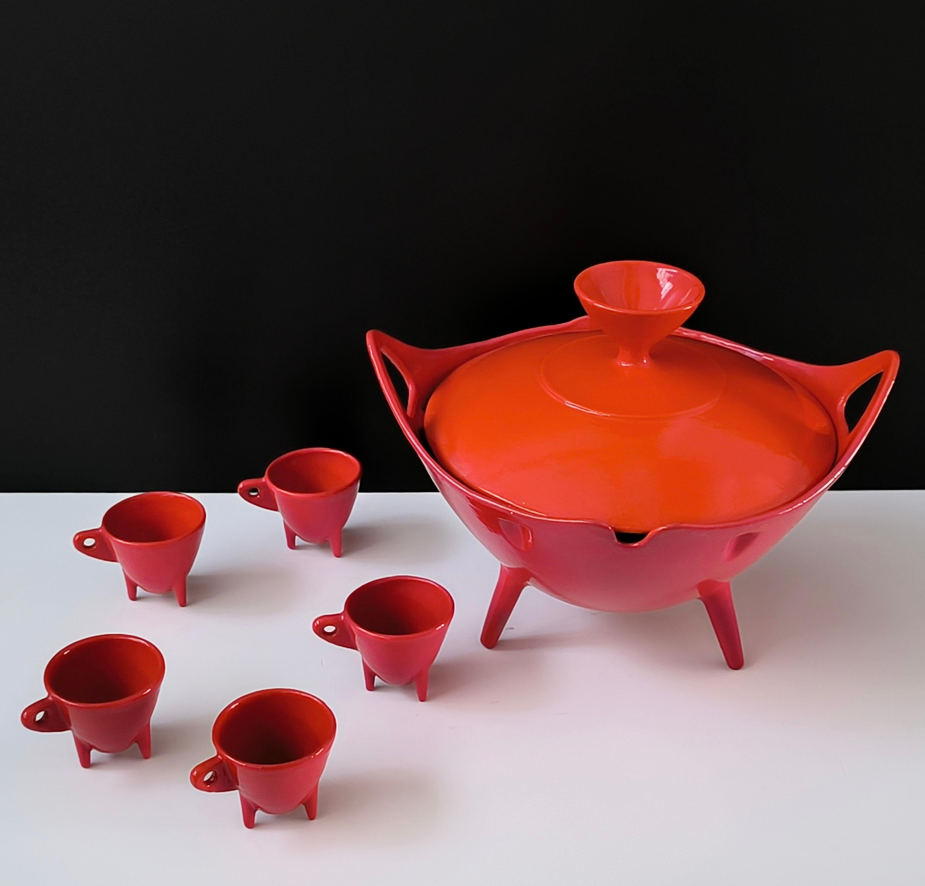 This striking set of vintage enameled cast iron serveware showcases bold mid-century modern design reminiscent of the legendary Timo Sarpaneva. Comprising a lidded cast iron bowl and five small handled cups, each piece features sleek lines, tripod