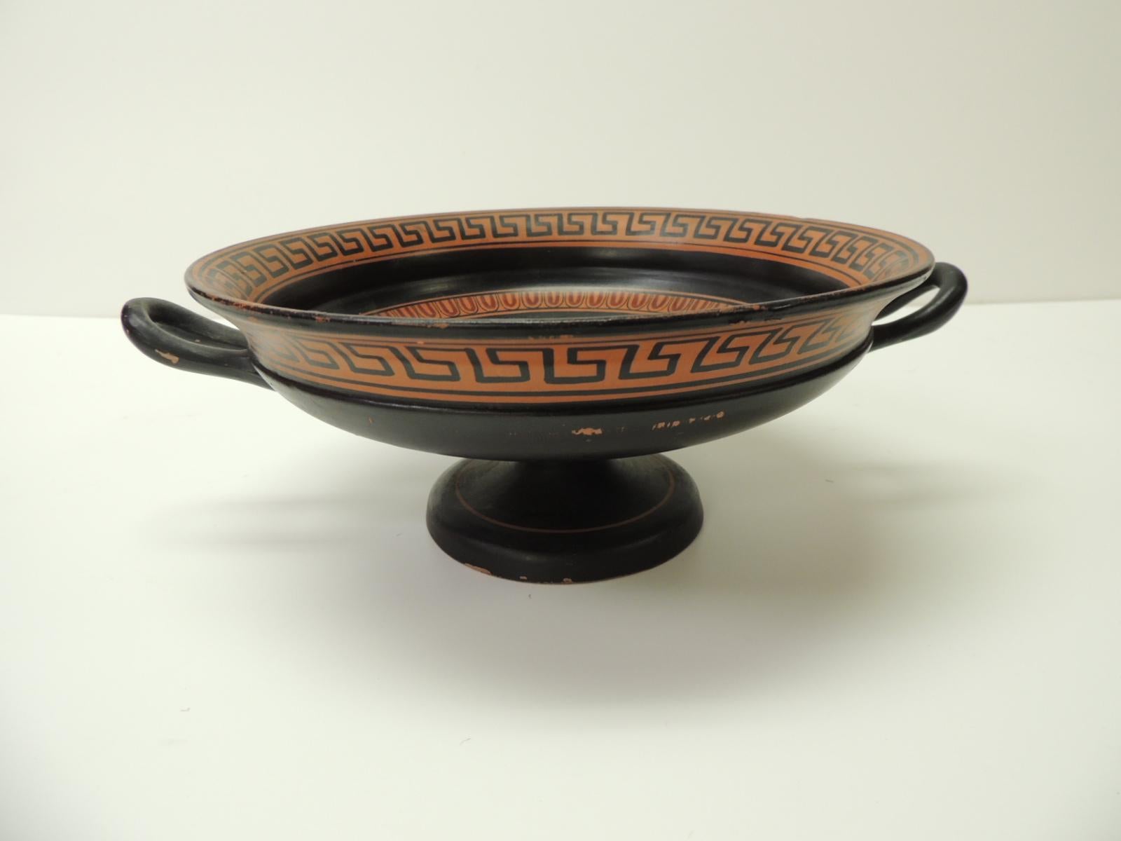Vintage encaustic hand painted Greek Terracotta centerpiece with Handles. Round decorative hand painted deep dish.
Orange and black dish depicting a naked Greek God seating on a huge jar. In shades of red, orange and black.
Signed: J.