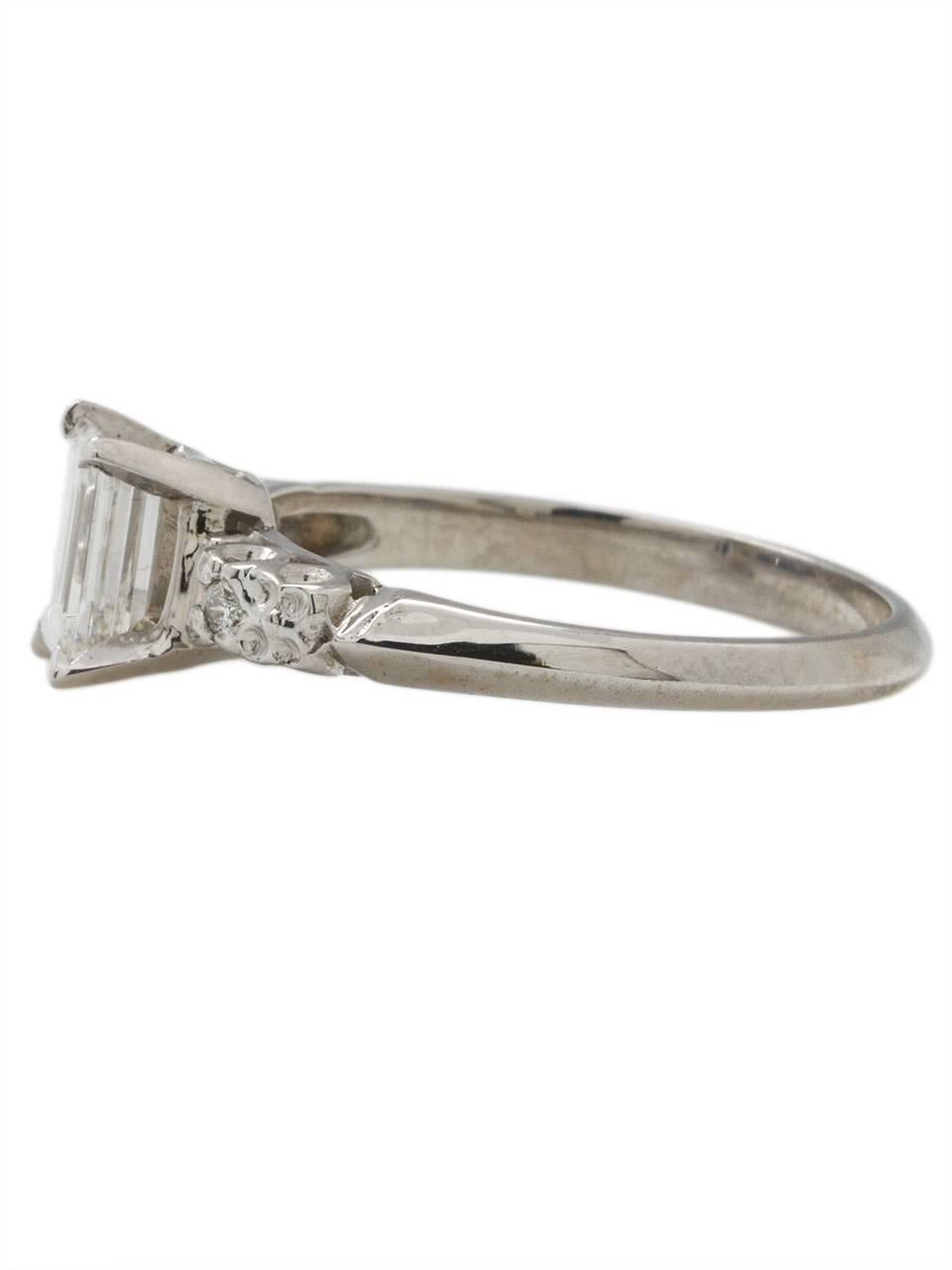 
Classic 1950s platinum engagement ring featuring a bright and lively EGL certified  0.63ct emerald cut, G-VS1. A softly  curved knife edge shank is accented by open scroll motiff galleries, and an elevated center setting, giving the stone maximum