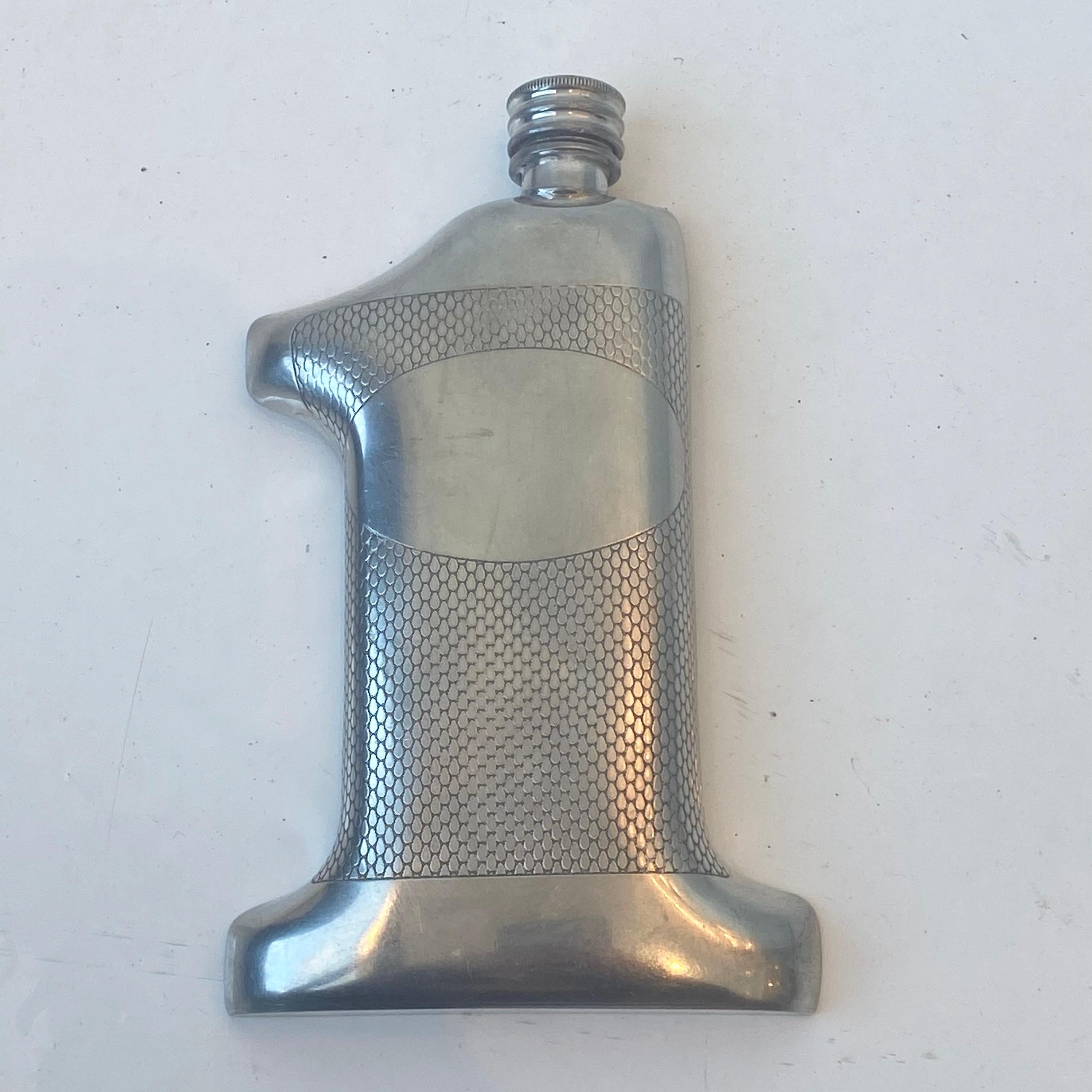 Unique vintage flask in the shape of the number one. Made of English pewter with teardrop shaped detailing on front. Label on bottom reads 