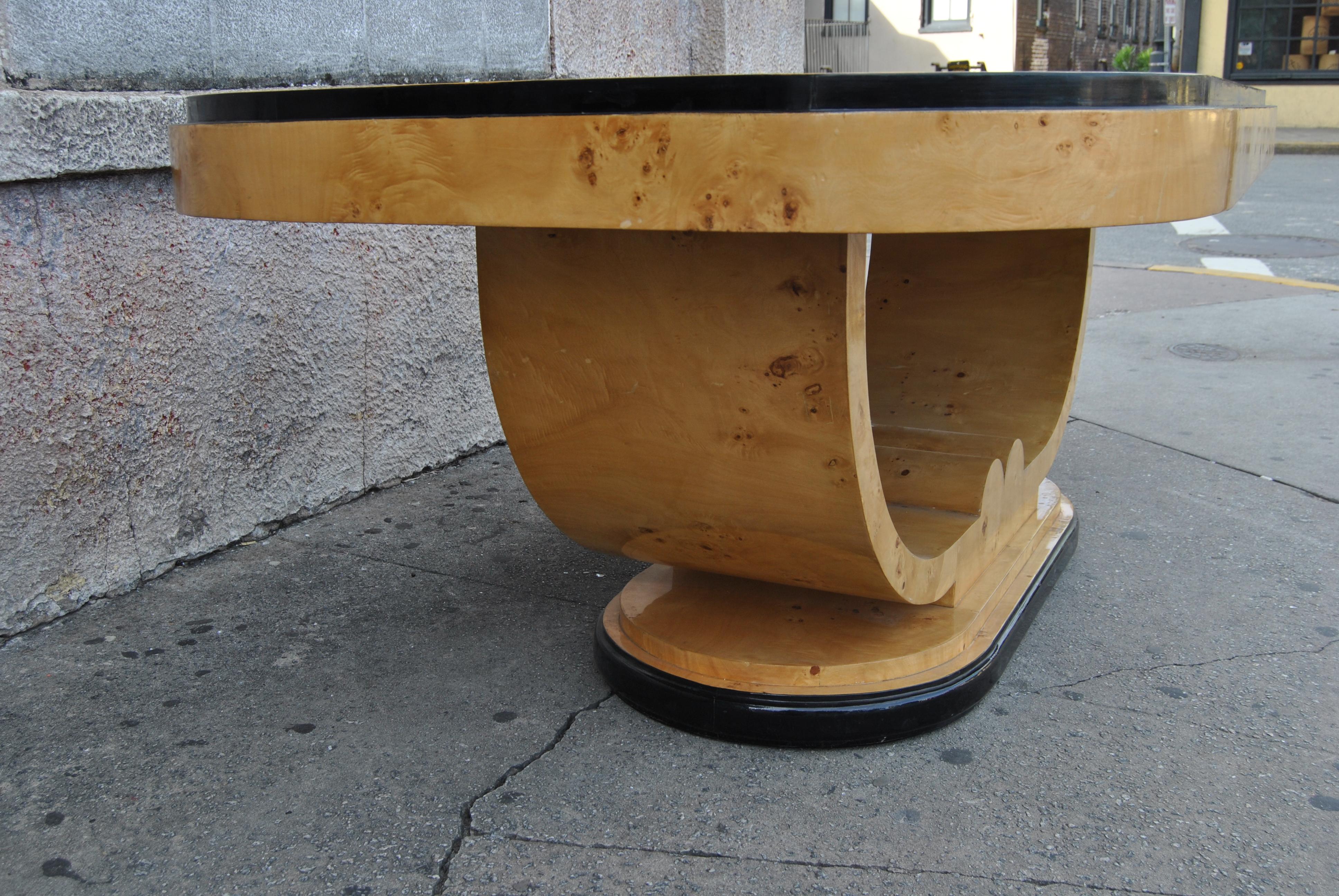 This is a table made in England, circa 1960. The table is in a beautiful high fashion Art Deco style. The table is made of an absolutely beautiful cut of bird's-eye Maple. It has a stunning U-shaped base that sits on a 2 step platform. The table has
