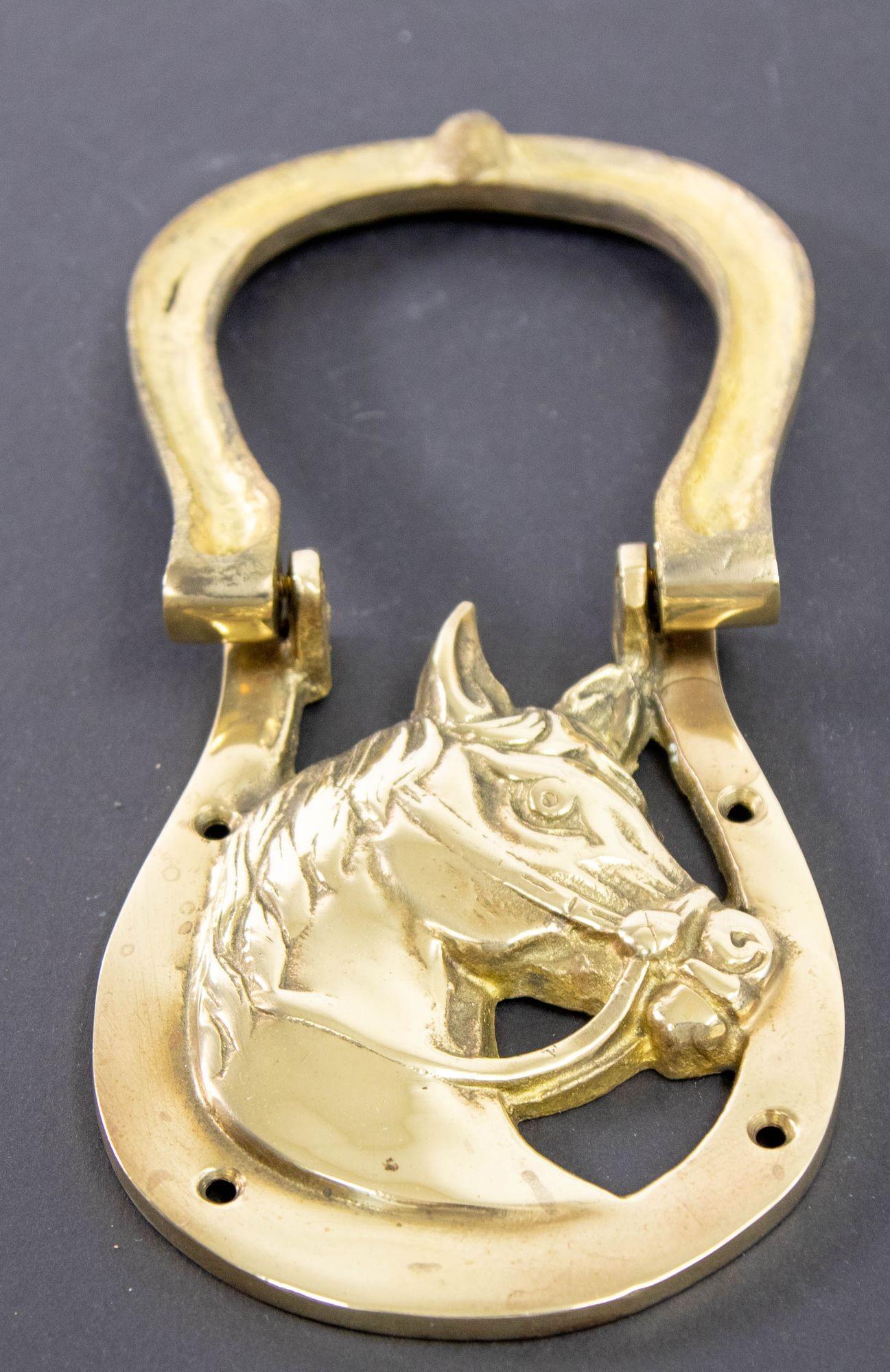Vintage English Brass Horse Head and Shoe Door Knocker.
1950s English Equestrian brass door knocker depicting a horse head in bridle in a large horseshoe.
A horseshoe door knocker made of cast brass with a bridled horse bust in profile framed inside