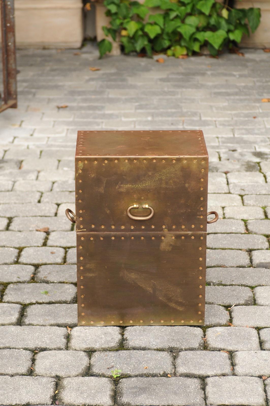 A large vintage English brass-plated box from the mid-20th century with handles and stud trim. This elegant English brass box is topped with an oblique-shaped lid connected to the rest of the body with a gilt chain, that opens thanks to a frontal