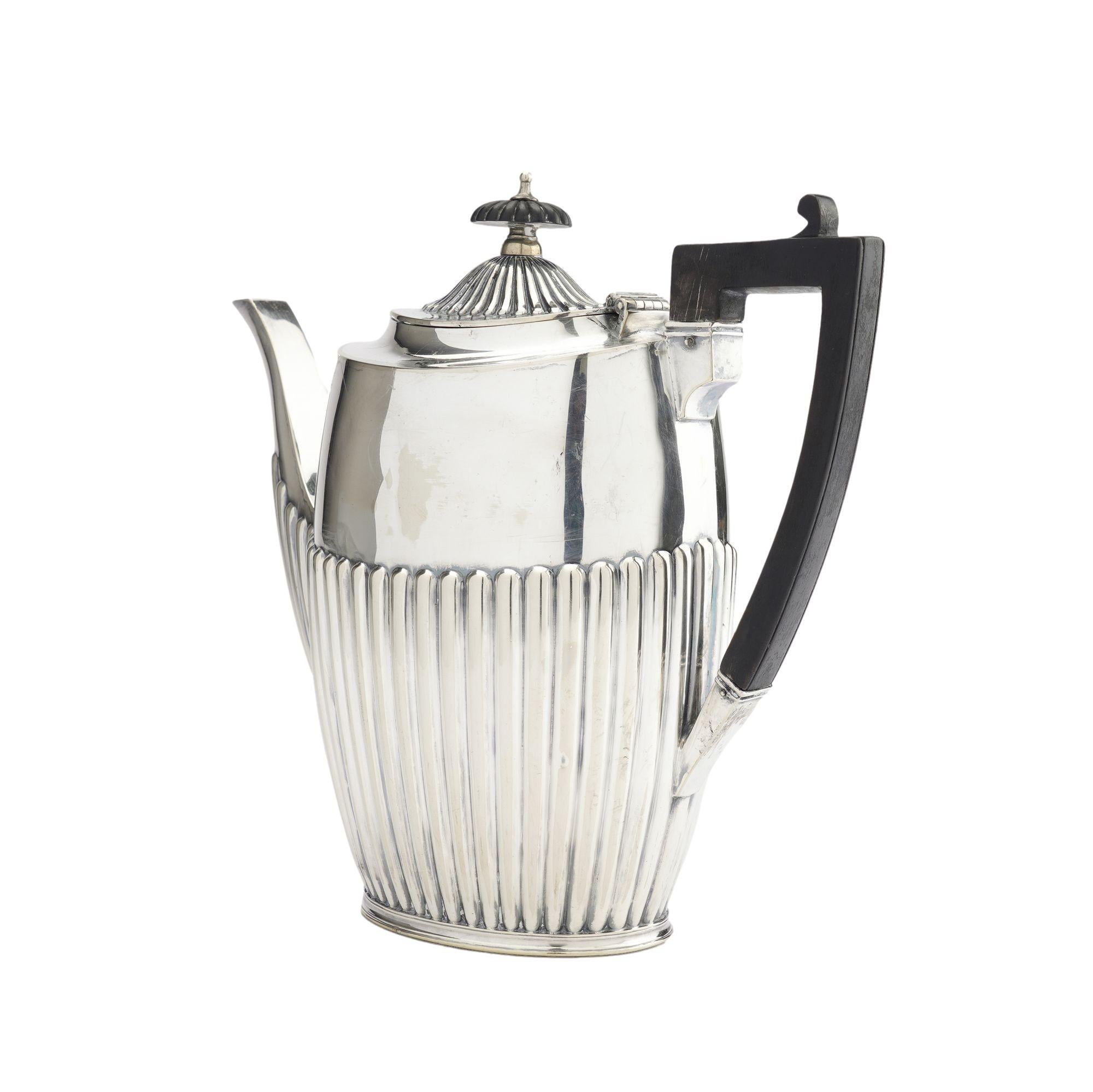 Edwardian Britannia plate coffee pot with a square carved ebonized wood handle in the Georgian taste. The pot has a reeded concave, oval hinged lid with a reel turned ebonized wood finial. The narrow bowed body has a reeded lower half including the