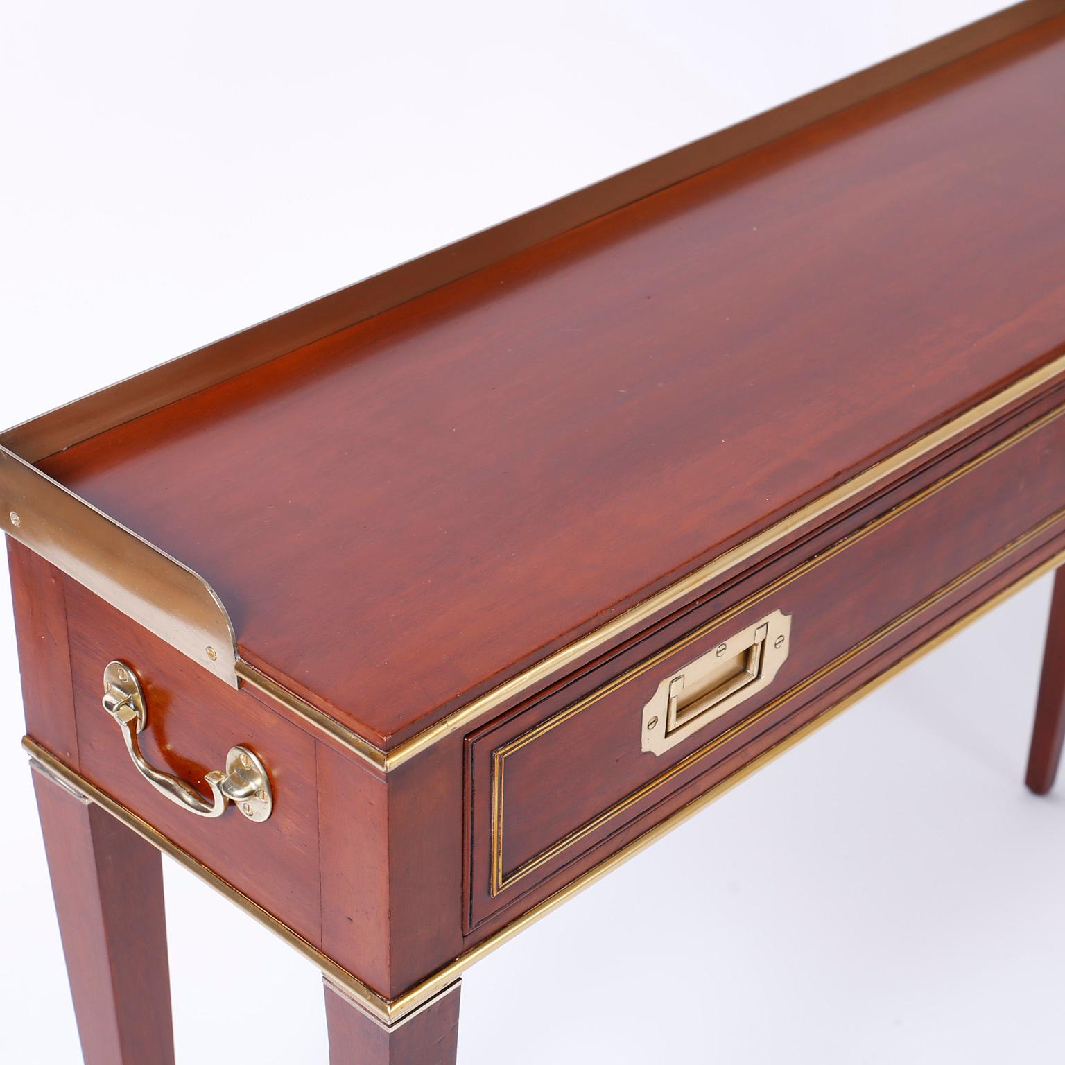 Refined mahogany campaign style server, console, or bar featuring a desirable slim profile, brass gallery, brass hardware, and a dapper form with sleek tapered legs.