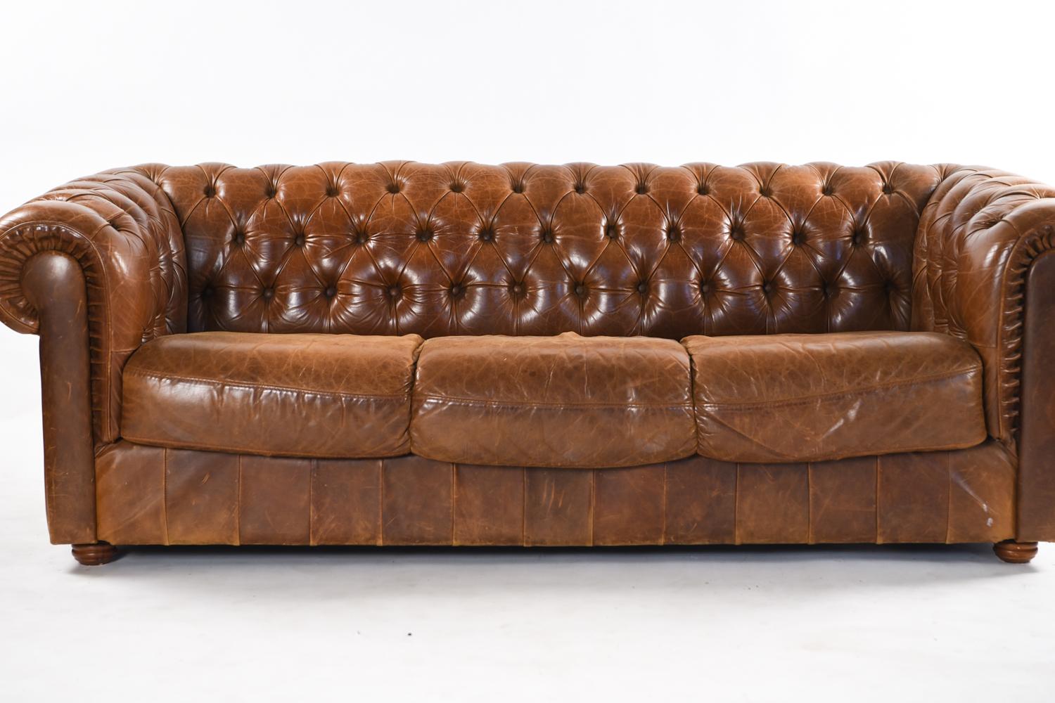 This three-seat vintage English Chesterfield sofa has a beautiful, original patination to the leather. With the traditional tufted surface and scrolling arms, this is a timeless piece that only gains style and comfort with age.