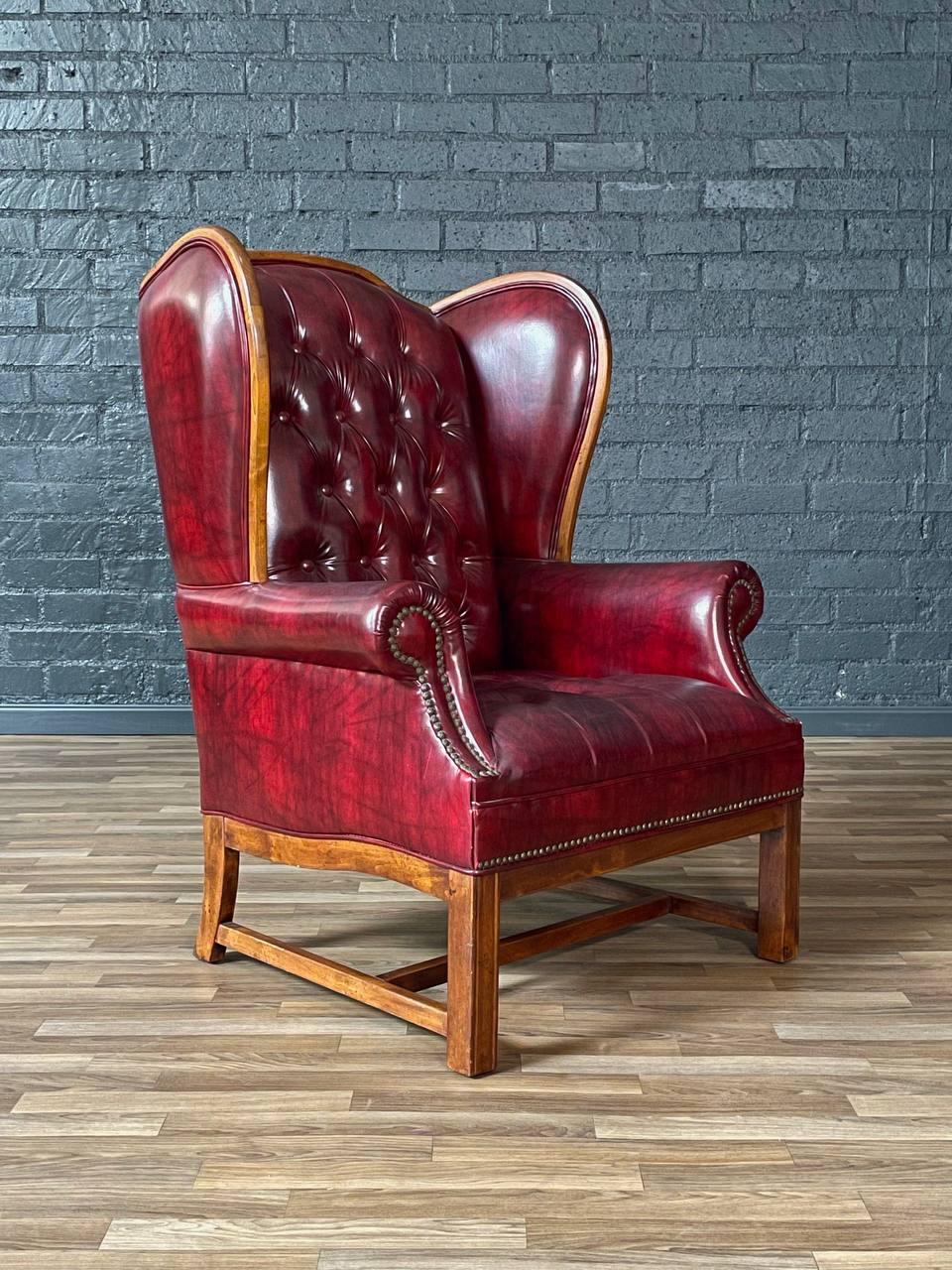 Condizioni: Condizioni originali d'epoca  
Materiali: Tappezzeria originale in vinile, puntine d'ottone, legno d'acero

Questa maestosa poltrona wingback, realizzata negli anni Sessanta, riproduce il classico stile Chesterfield inglese con la sua