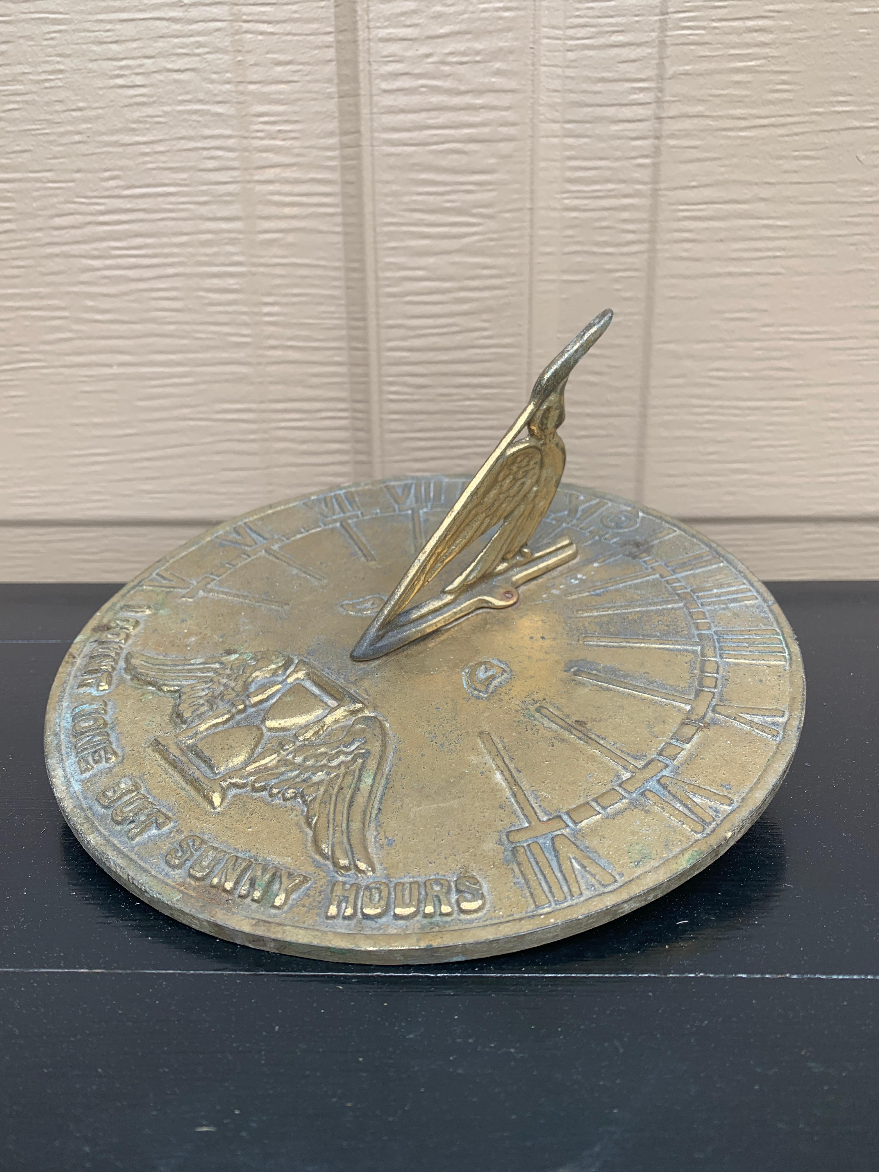 A stunning vintage iron garden sundial featuring Roman numerals and an hourglass with wings, reading 