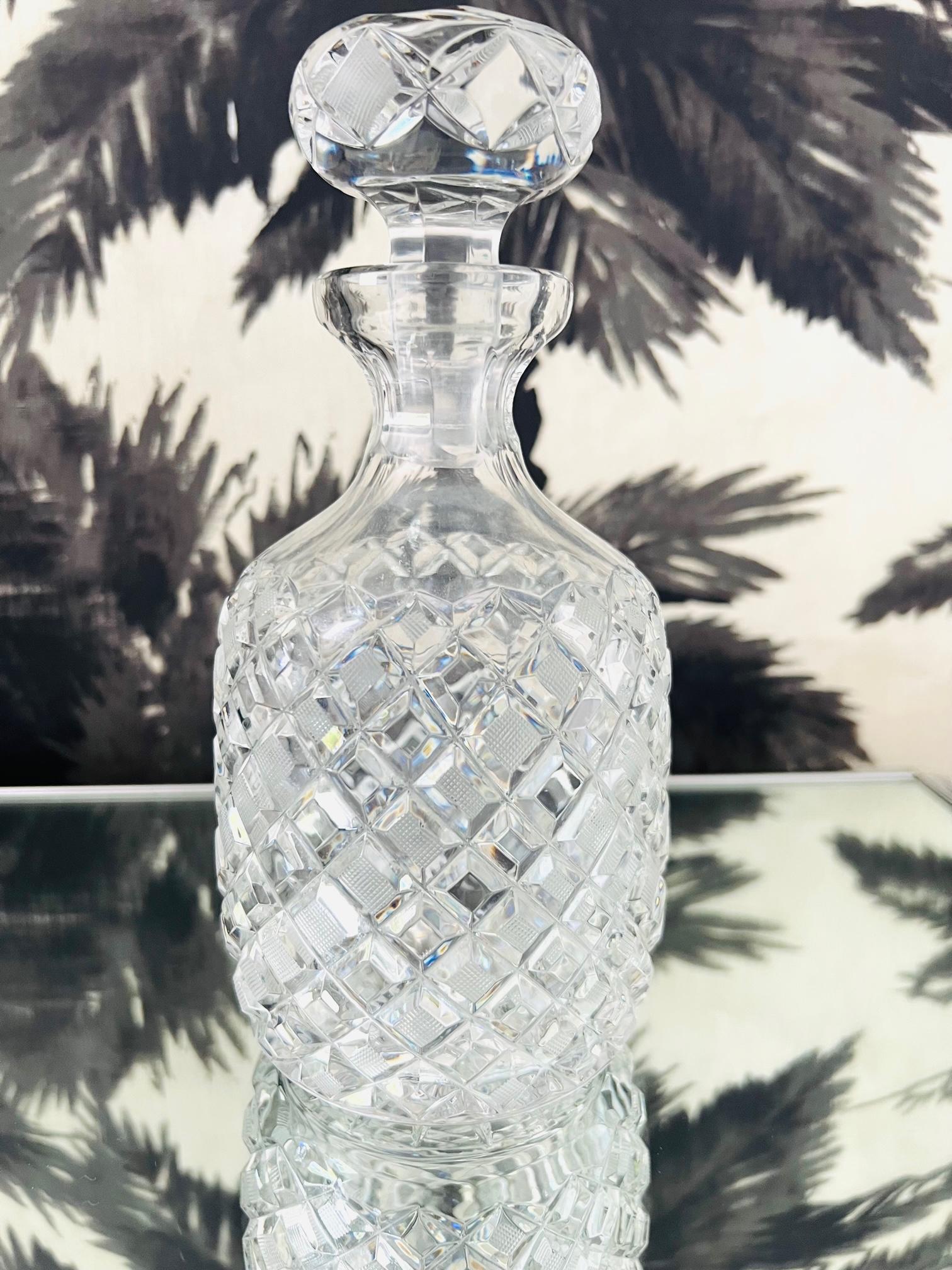 Vintage cross hatched crystal decanter with stopper. The decanter features elegant diamond patterns with both textured and smooth surfaces. The stopper has faceted teardrop designs along the top and echos the diamond pattern of the bottle. The