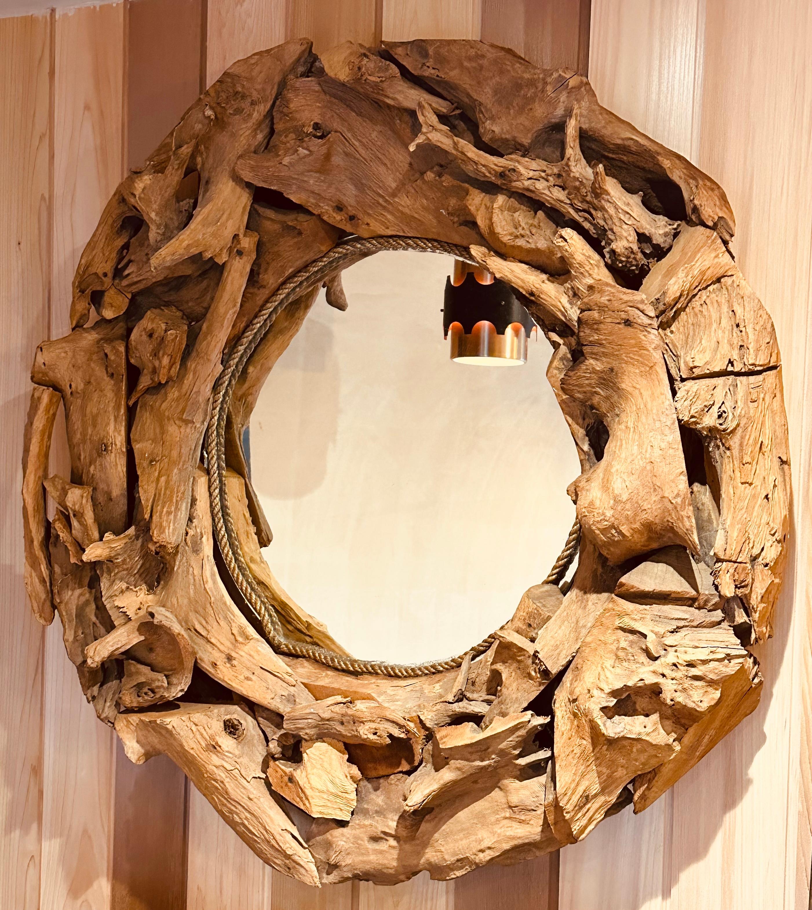A large, well-made, and very heavy, vintage driftwood framed glass wall mirror. The frame is constructed from Individual pieces of driftwood tree root that have been handcrafted into a textured and rustic design surrounding the glass mirror.  A