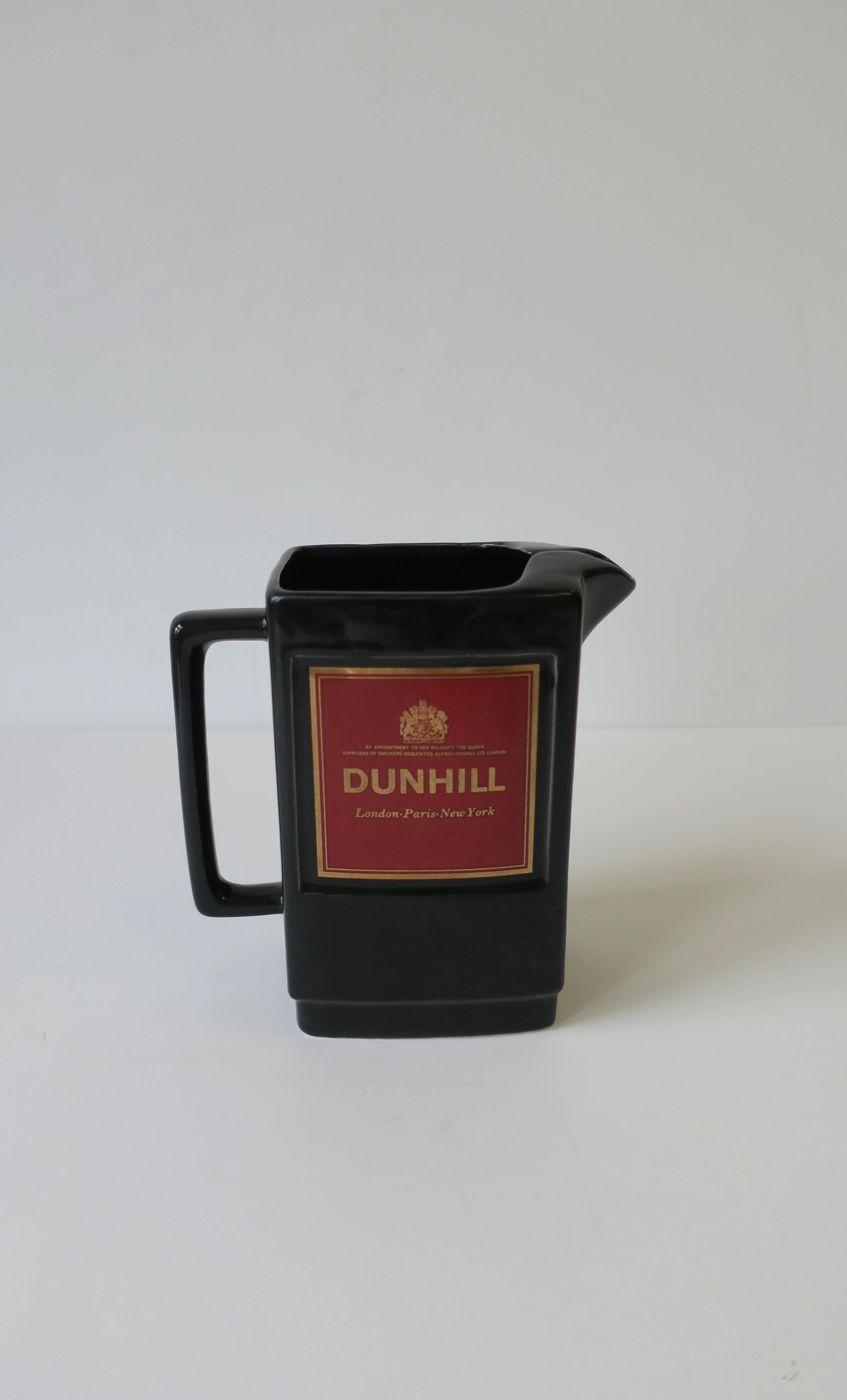 A great black, gold, and burgundy red liquor, spirits, or water decanter pitcher from iconic luxury retailer Dunhill, circa mid-20th century, England. Reads on front 
