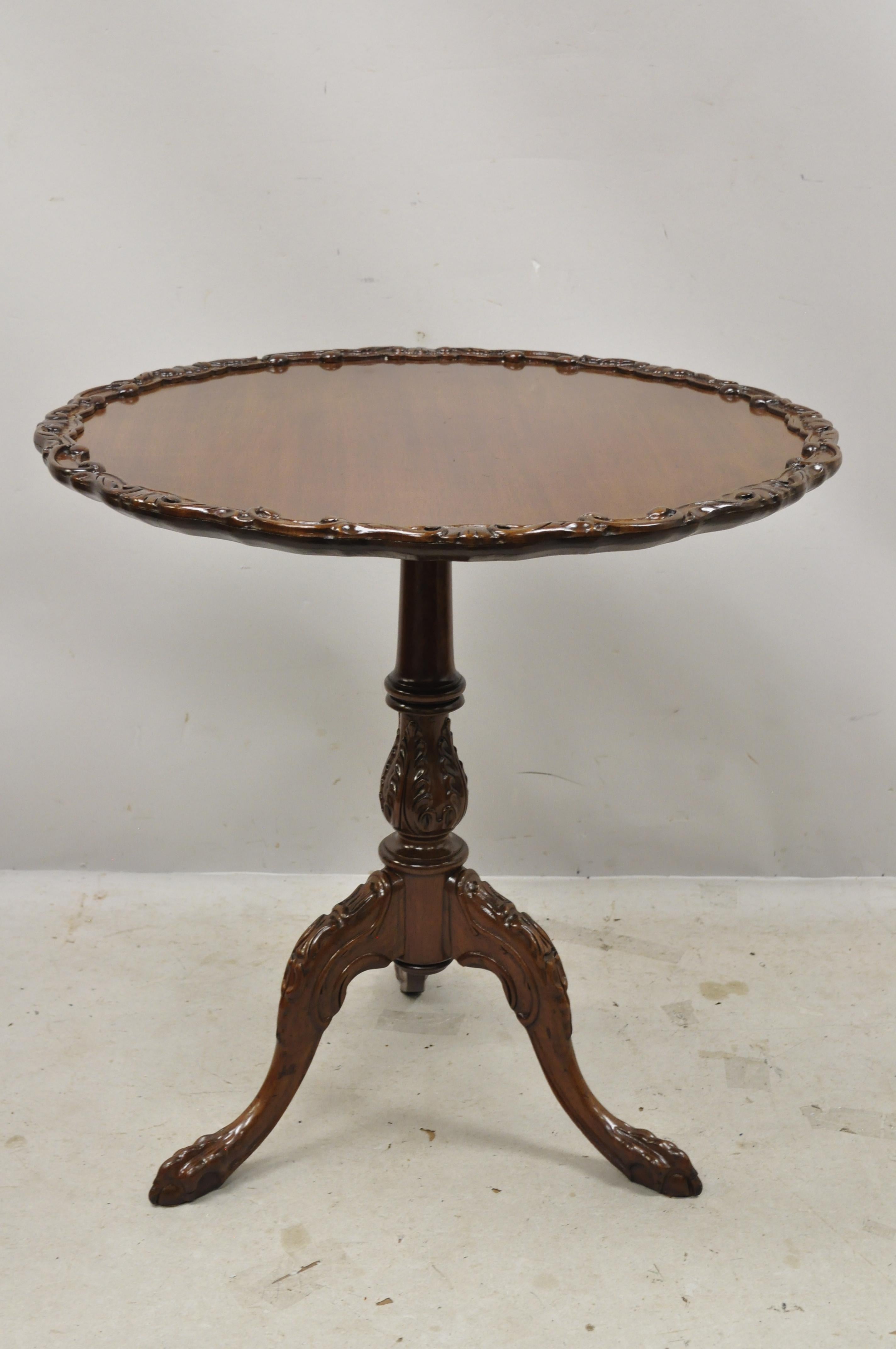 Vintage English Georgian Chippendale mahogany pie crust tilt-top tea table. Item features pie crust carved edge, carved pedestal base, solid wood construction, beautiful wood grain, nicely carved details, carved ball and claw feet,
circa mid-20th
