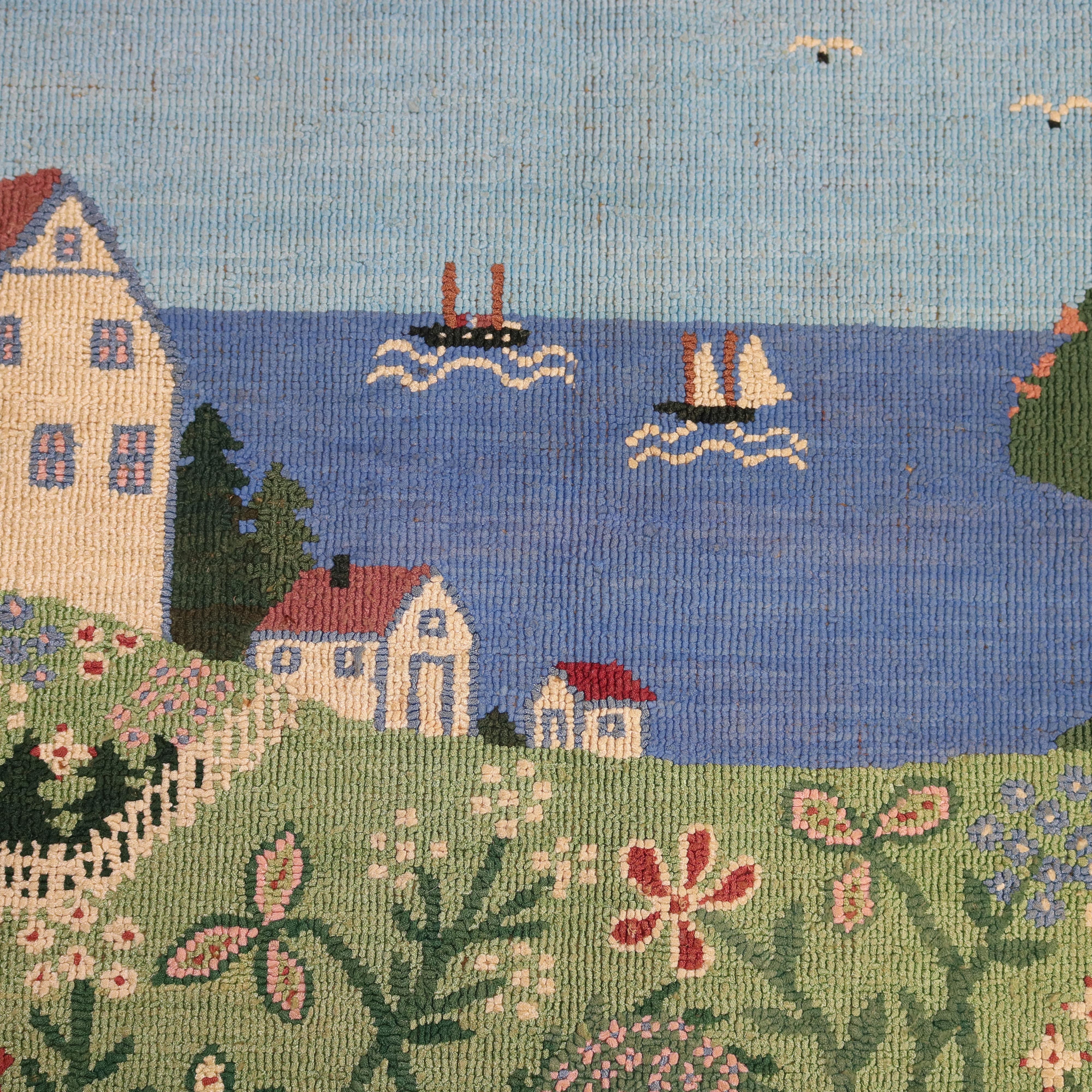 A vintage Newfoundland Grenfell Labrador hand hooked area rug offers scenic view of village and harbor with structures, flowers, boats and birds, 20th century

Measures- 18