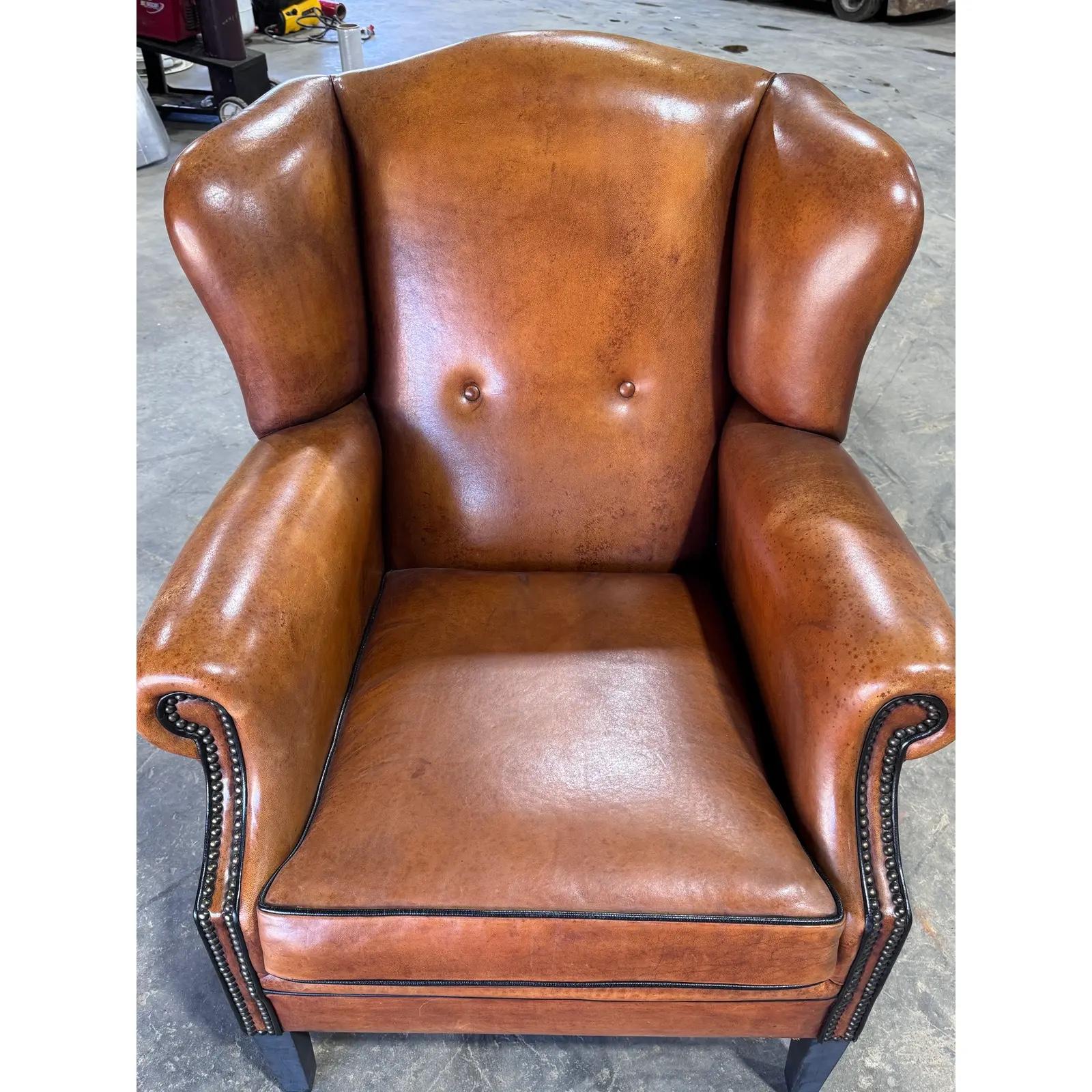 Ce magnifique fauteuil à oreilles anglais est fabriqué en cuir de mouton de haute qualité, avec des clous et un passepoil noir. A notre avis, vous devez avoir un tel fauteuil à oreilles en cuir de mouton dans votre maison ! Il arbore une belle