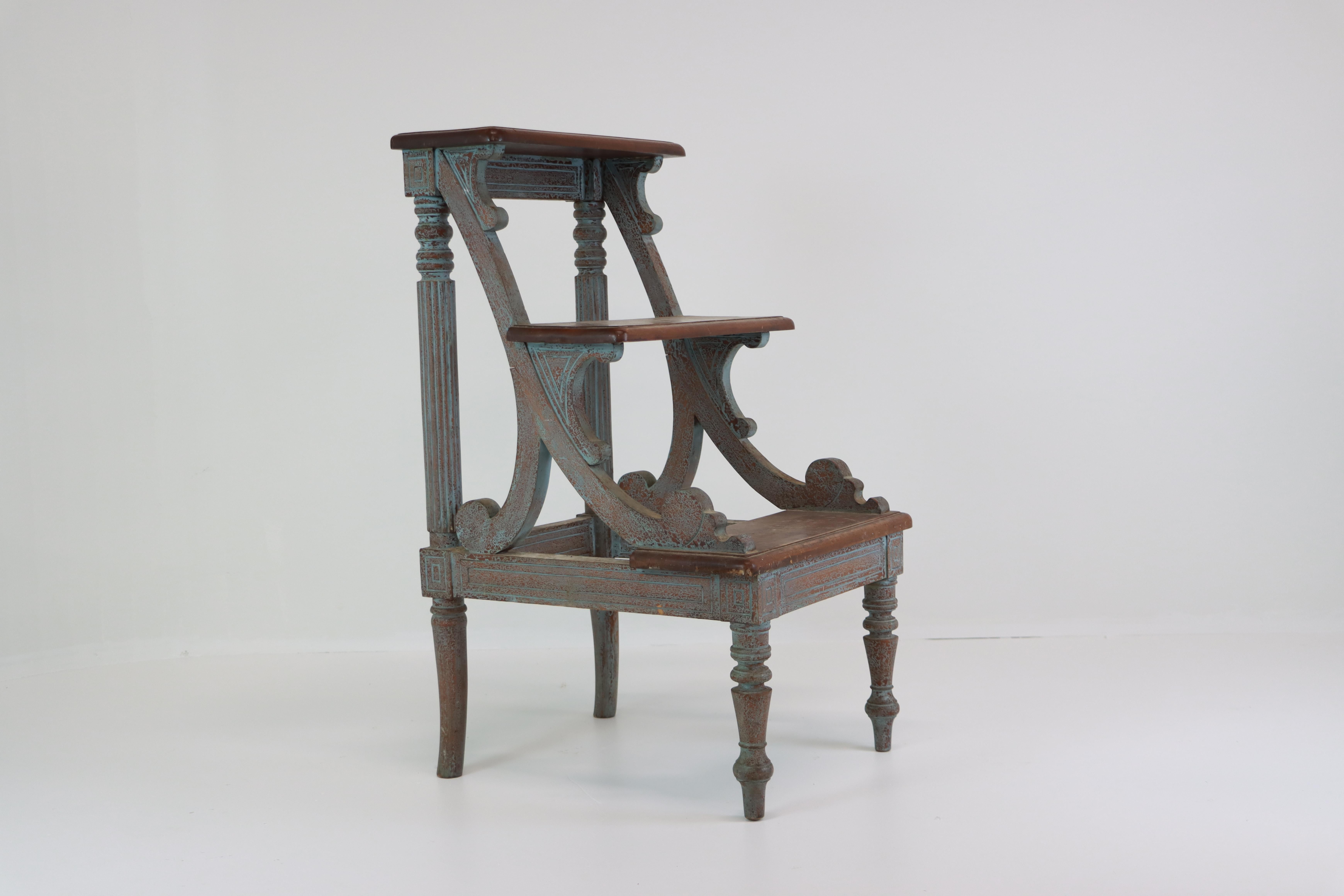 A well-proportioned set of 20th century European library steps featuring neoclassical-inspired turned and fluted legs, incised square corner details, and shaped scroll side supports. Constructed in solid hardwood, the piece retains a later