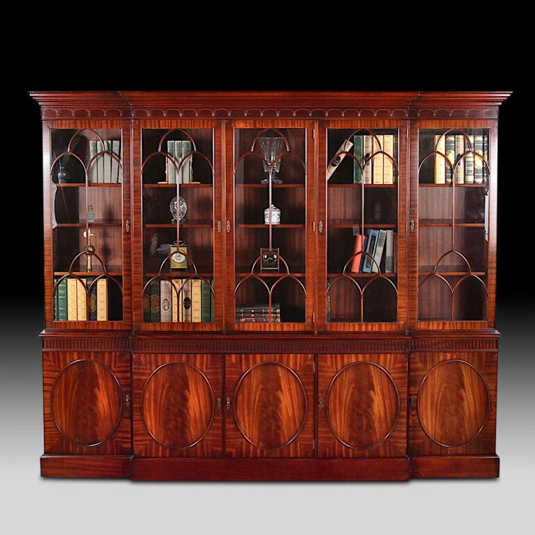 Vintage English mahogany Georgian-revival breakfront bookcase with five upper glazed doors opening to adjustable shelves and a lower section with five flame mahogany-veneered doors. Elegant carved and molded details to the crown and