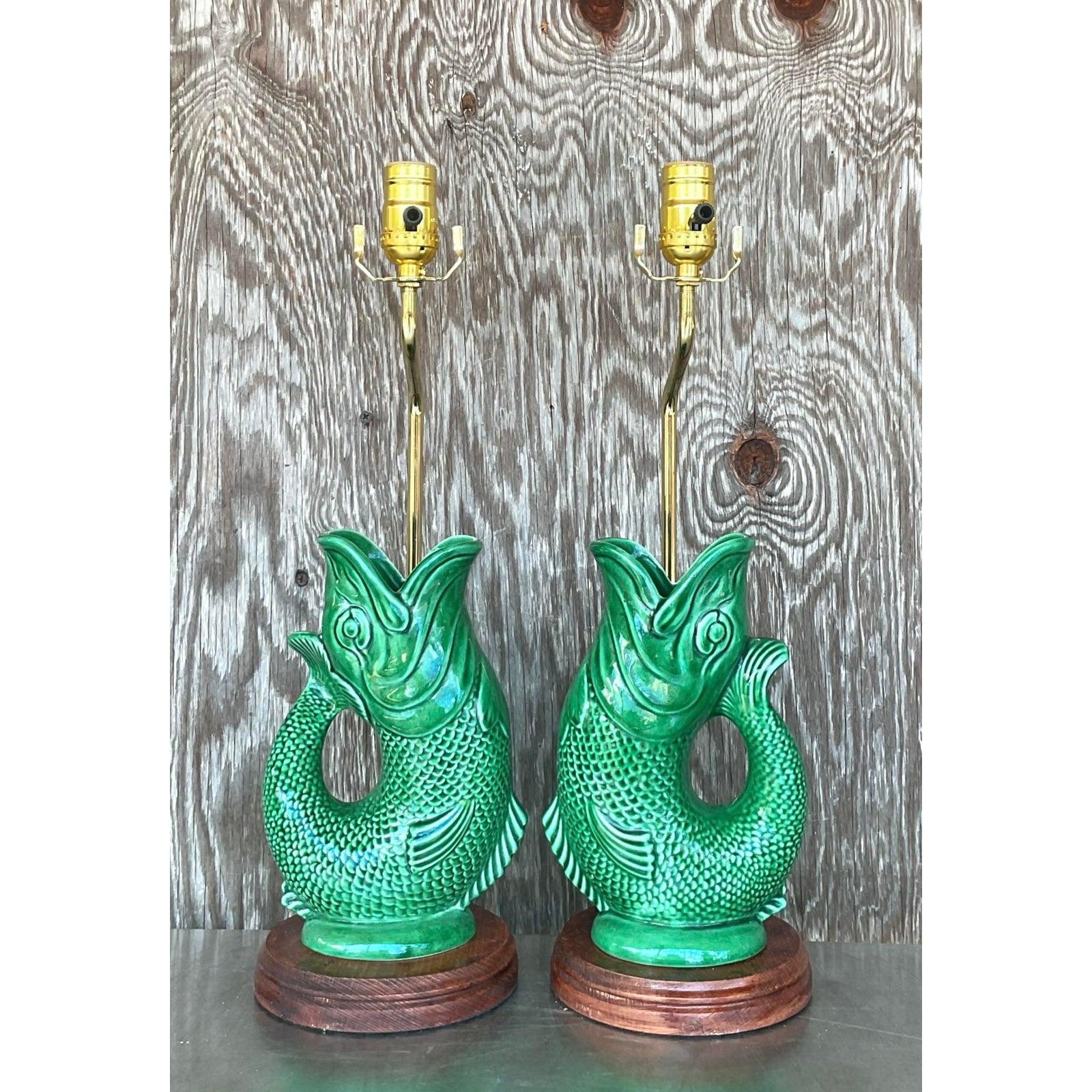 Dive into bold design with this whimsical pair of vintage English Majolica koi fish lamps. Richly glazed in a vivid emerald green, each sculptural lamp captures the graceful movement of a leaping koi in classic majolica ceramic, mounted on polished