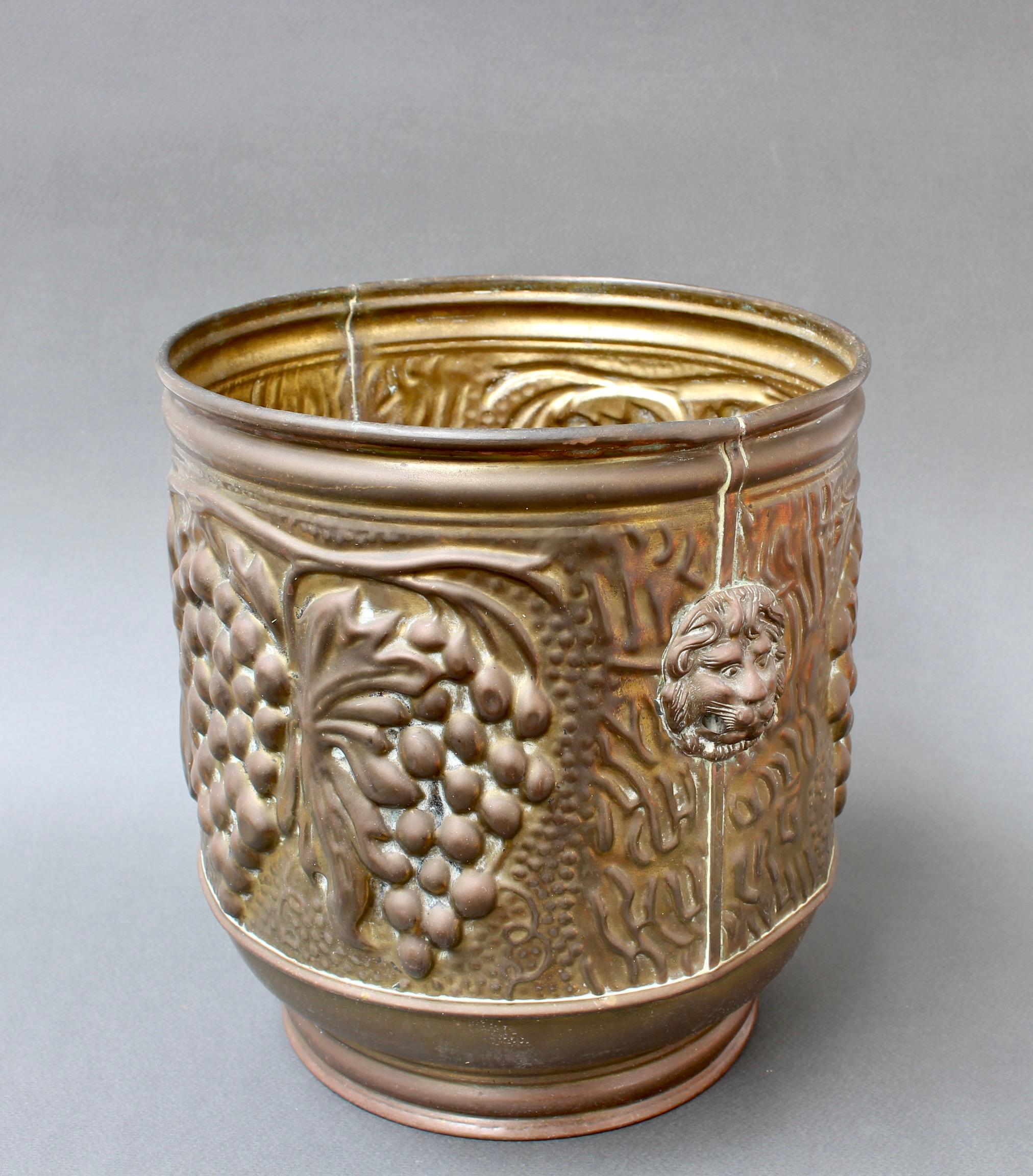 Vintage English metal ice bucket or cachepot (circa 1930s). Lion motif handles accent this interesting vintage piece with grape bunch motif. The piece was originally intended to be used as a wine cooler. It may be also used as a planter or simply as