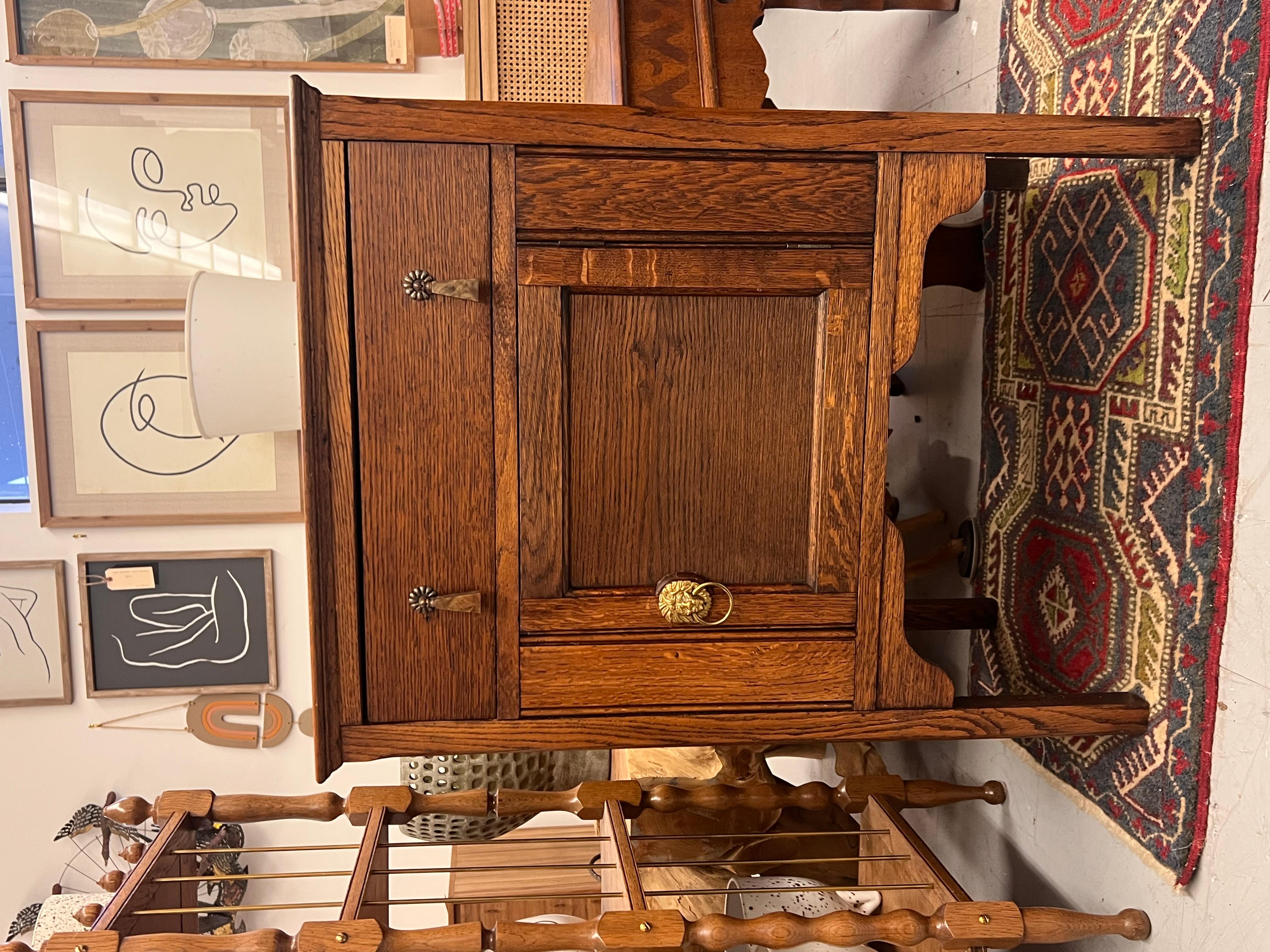  The oak cabinet showcased in the images is a striking example of vintage craftsmanship, likely reflecting the Arts and Crafts or Mission style. It features a rich oak finish that highlights the wood's natural grain, complemented by clean lines and