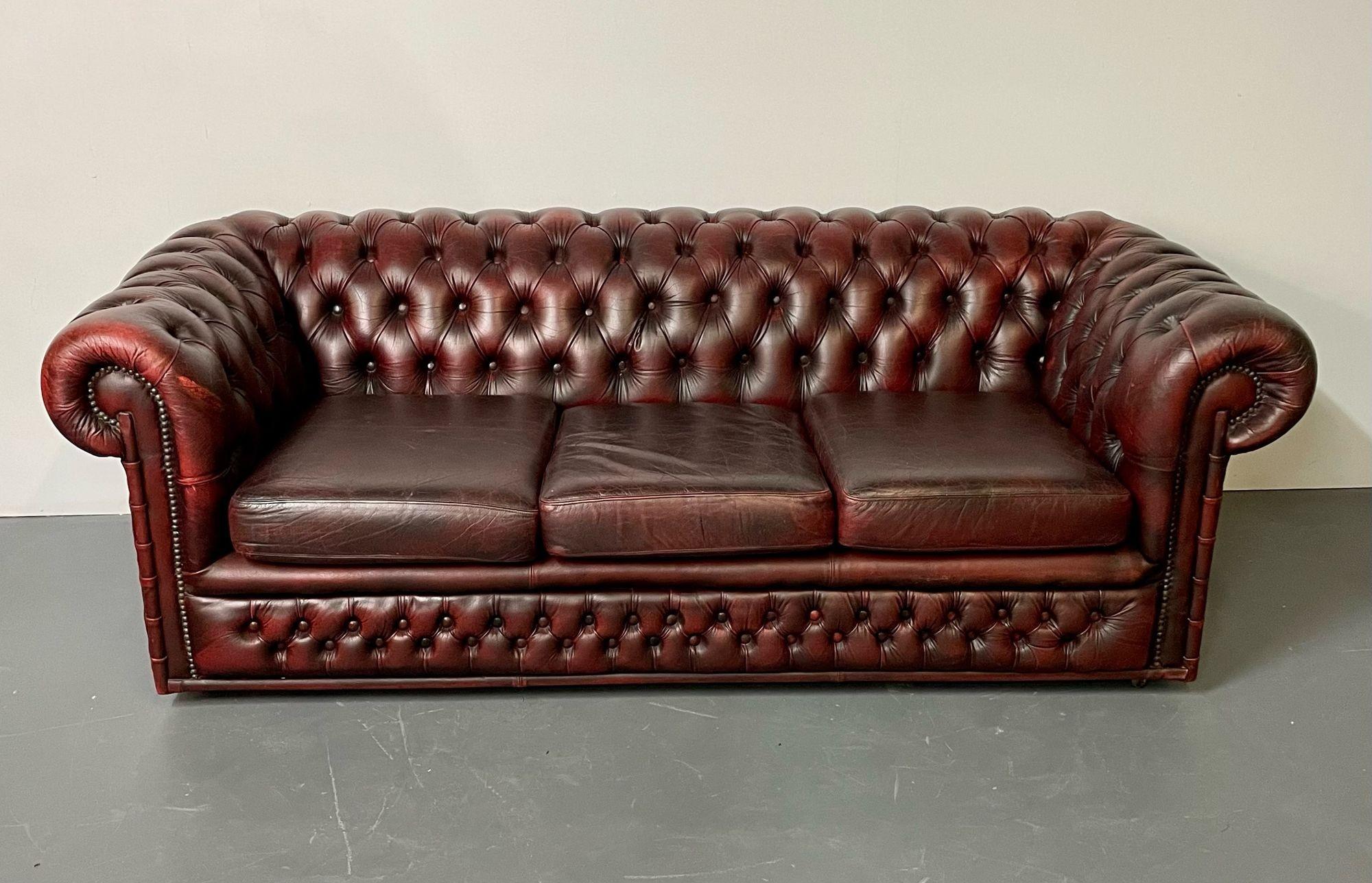 Georgian English oxblood red leather chesterfield sofa, faux bamboo front, tufted.
An English three seater Chesterfield sofa upholstered in oxblood red leather. Diamond tufted on the back and front skirt, secured with a brass nail-head trim.