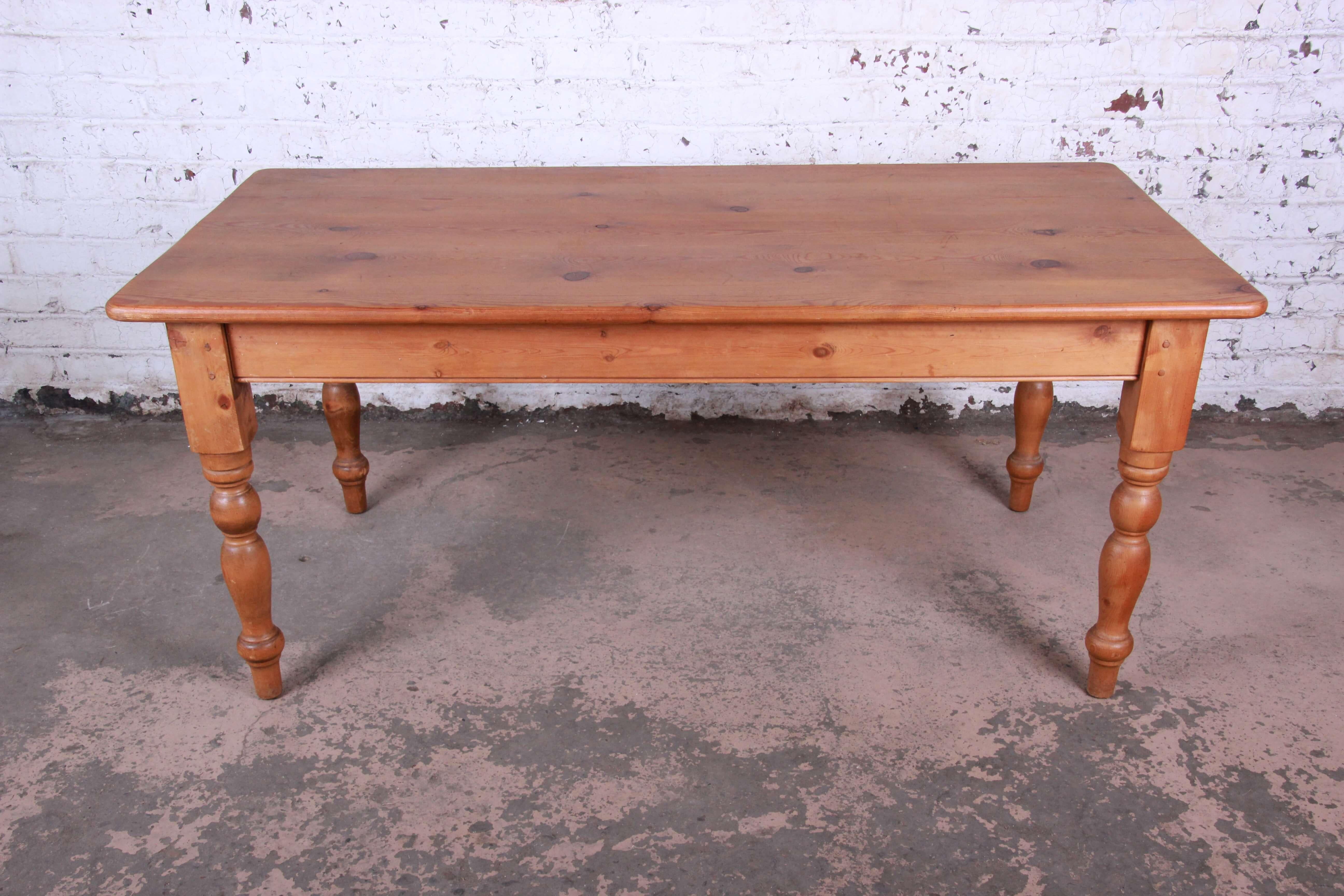 Offering a nice Primitive style English pine harvest table. The harvest table has a solid knotty pine top which is sturdy and solid with a nice Primitive look. It was produced circa 1950s in England and has a few use marks on the edges from age and