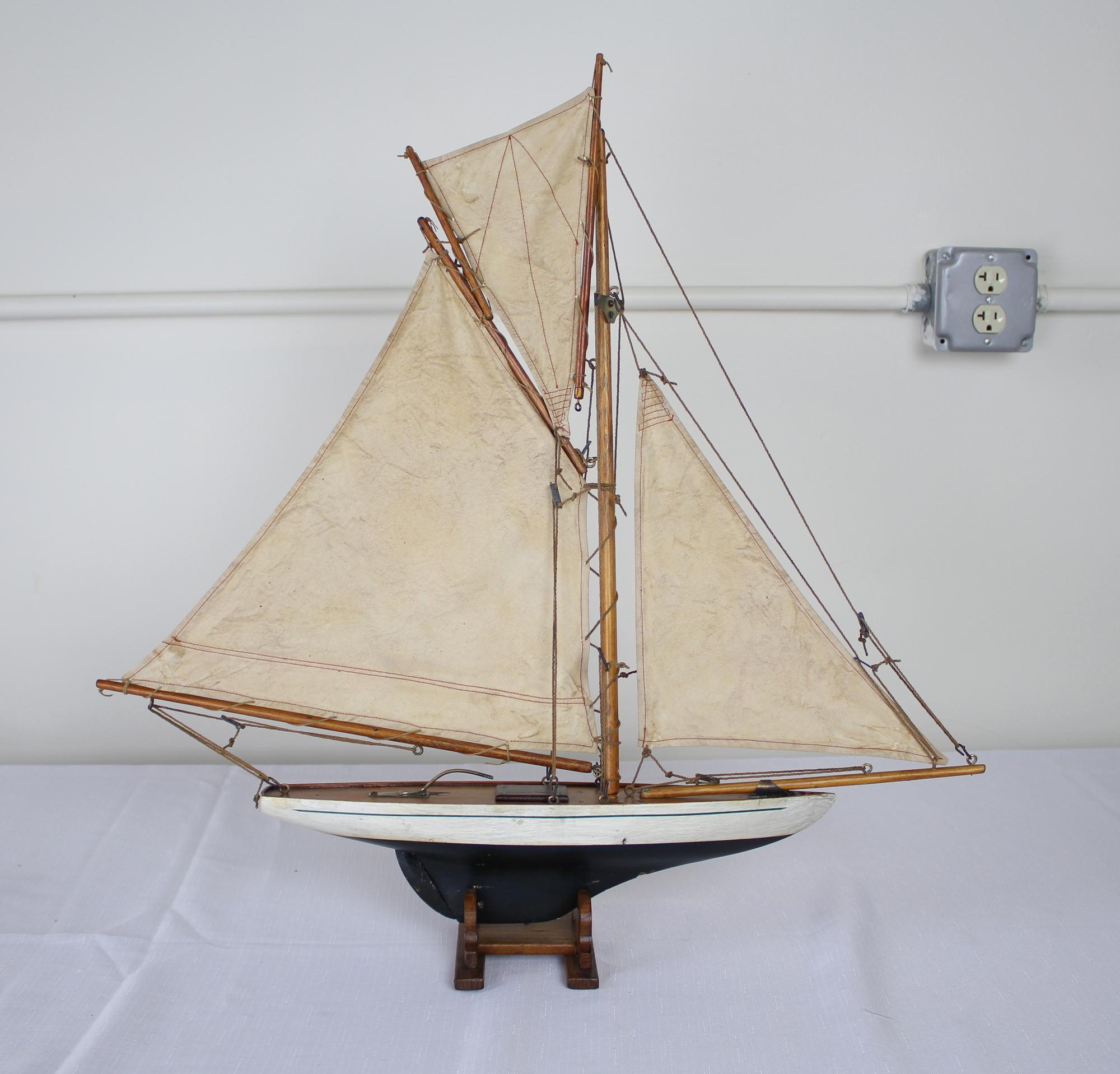 A charming vintage model yacht with sails made from old sail cloth and original brass accents. Stand is recent to hold the ship upright and stabile.