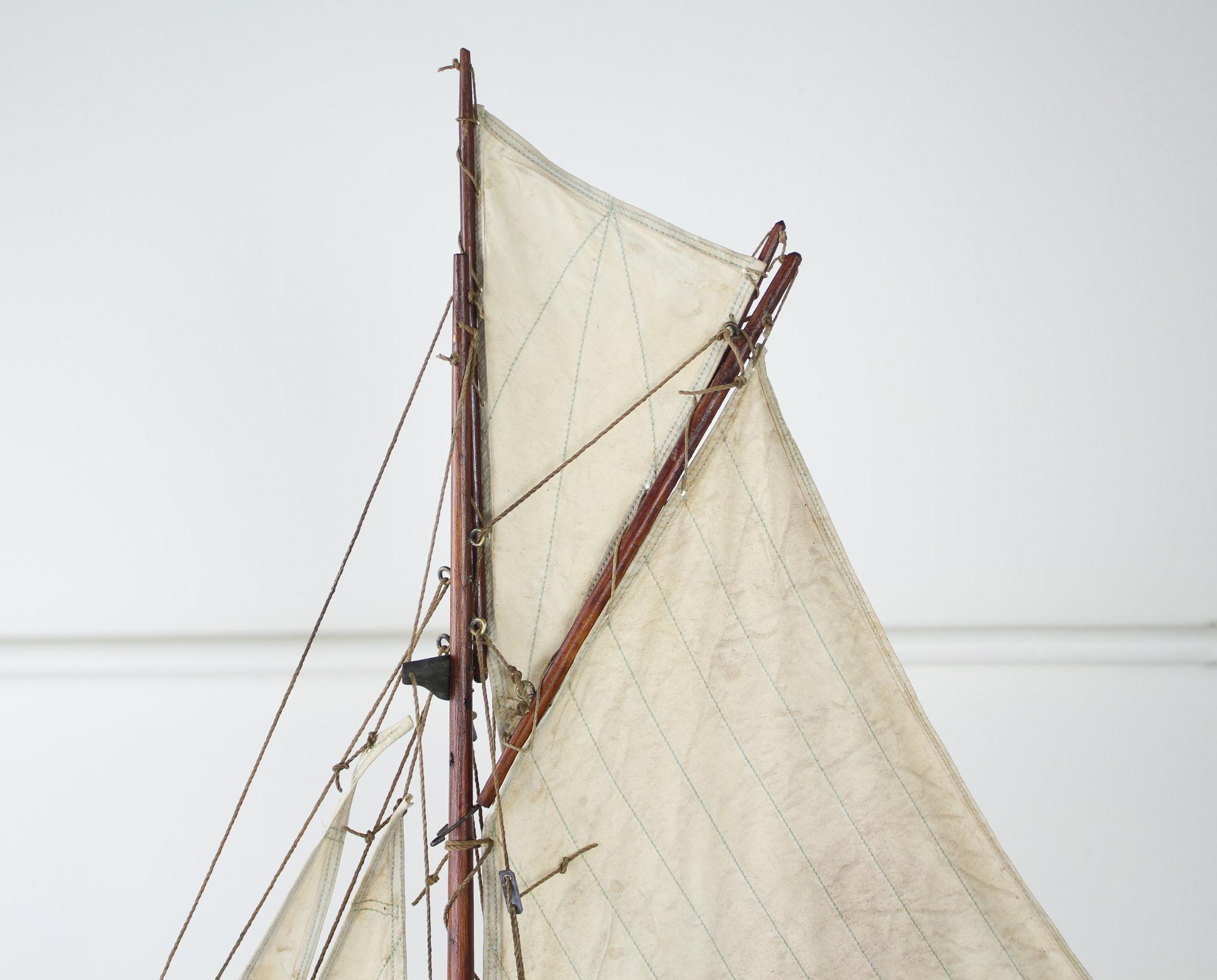 A charming vintage model yacht with sails made from old sail cloth and original brass accents. Stand is recent to hold the ship upright and stabile.
         