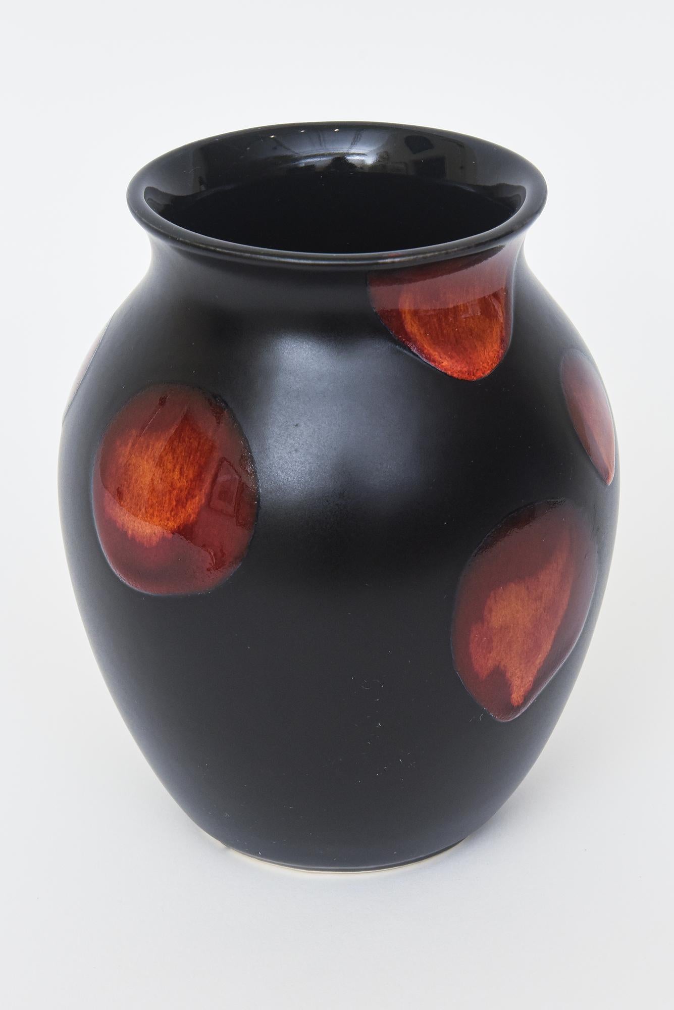 This lovely small bulbous vintage ceramic vase is from the 60's and made by Poole Pottery from England. It has red abstracted blobs against the black background randomly placed.  It is hallmarked on the bottom with a dolphin cartouche with many