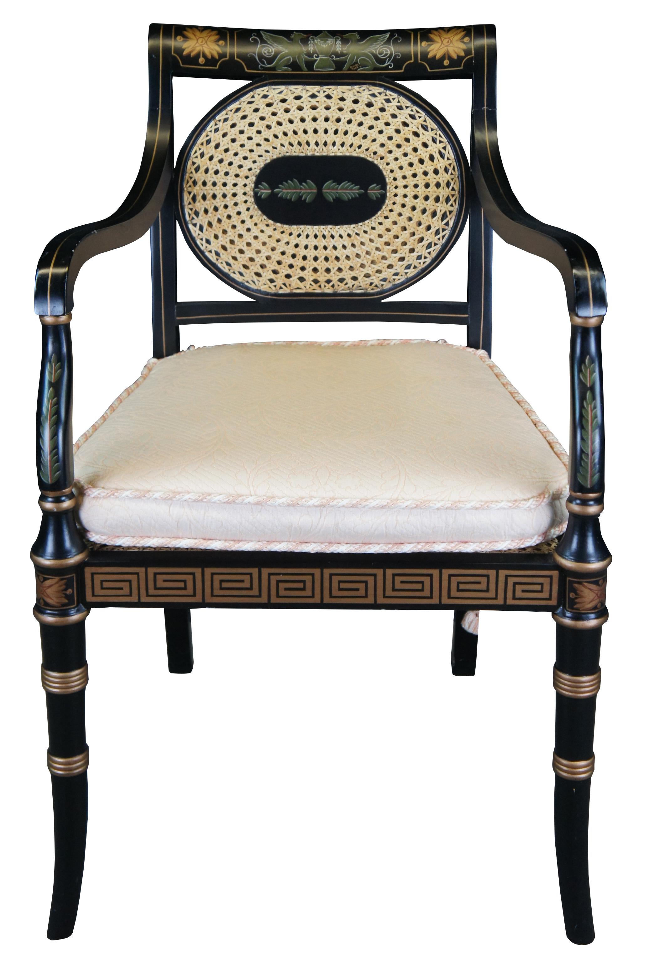 English Regency style black lacquer arm chair with cane seat and back. Features golden ribbed trim, a Greek key apron, stringing, leaf paintings and a pair of griffins holding an urn along the top. Features a removable slip seat with braided cording